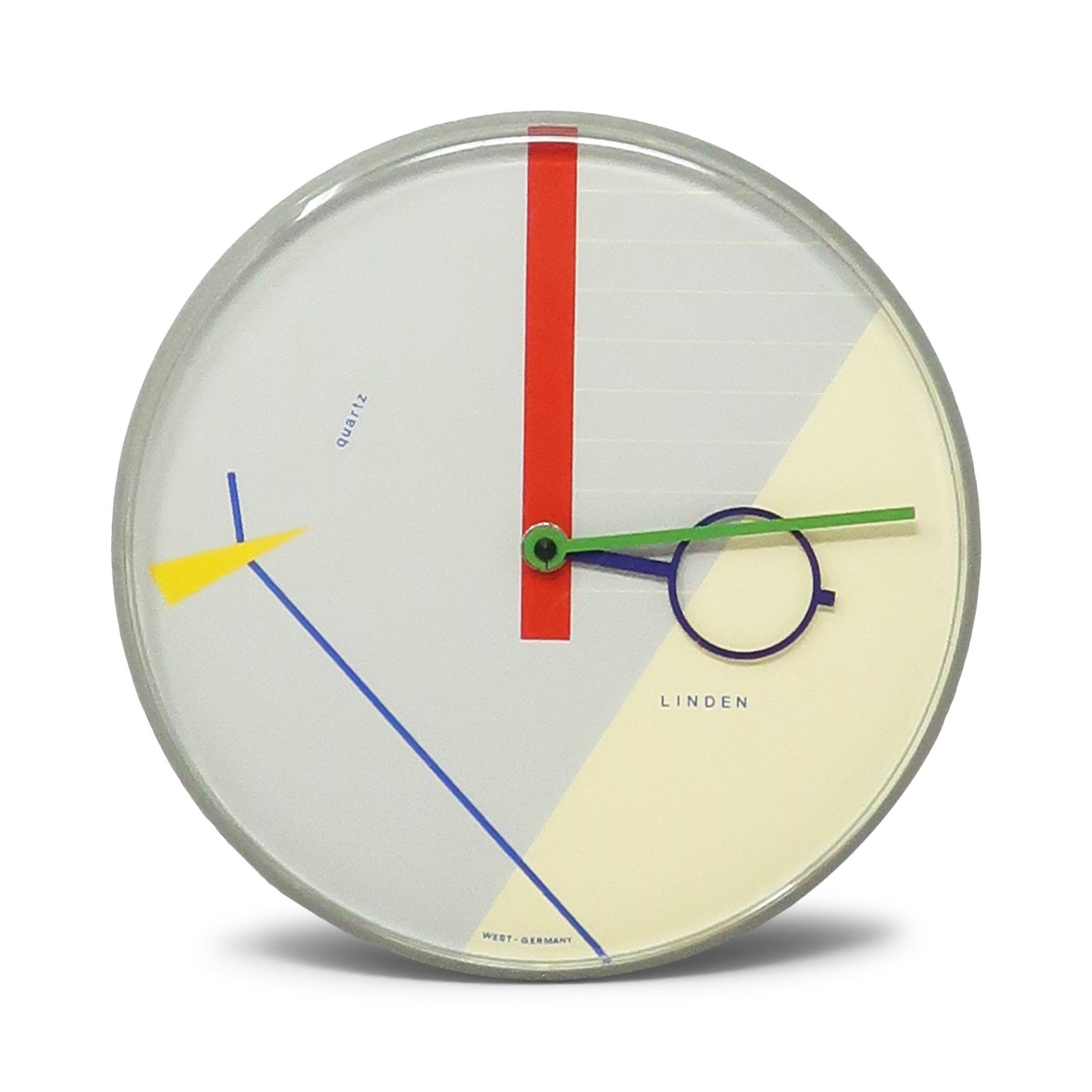 A beautiful postmodern wall clock from the 1980s by West German clockmaker Linden.  It has a gray case, gray and off-white face with geometric accents, and blue and green hands,  Striking contrast and fantastic pop of colors with blue, red, and