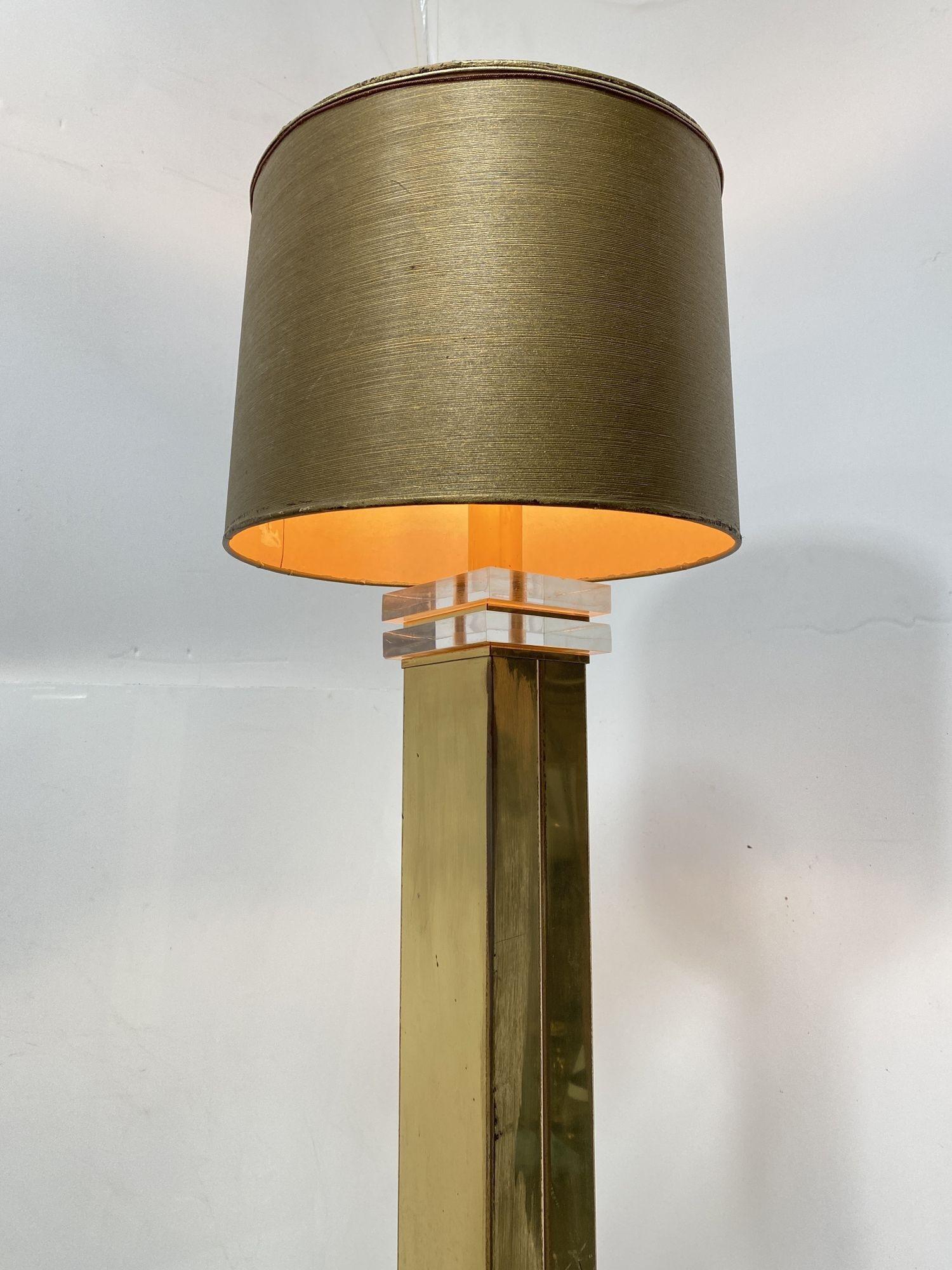 Ce lampadaire moderne de haut style en acrylique Lucite et laiton, Circa 1970, présente un corps en laiton avec une moitié inférieure en Lucite transparente, créant un effet de flottement. Le haut de la lampe présente un design Lucite à deux niveaux