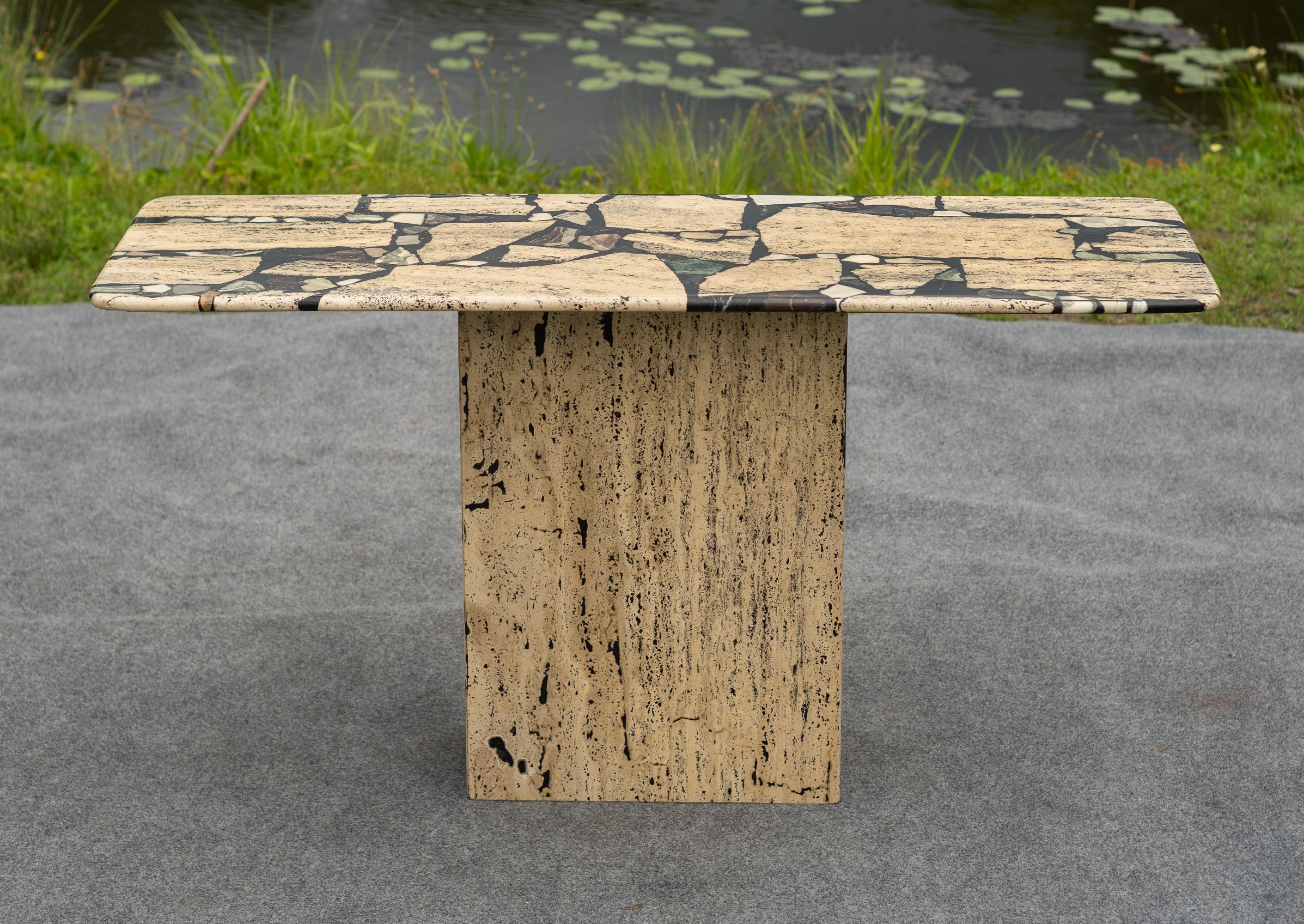 Designed and made in Italy, this peice was probably made by Stone International. The main feature of this table is the material, made mostly of travertine inlaid with many smaller pieces of varied marble. Sections of rosso, verde, calcatta, and