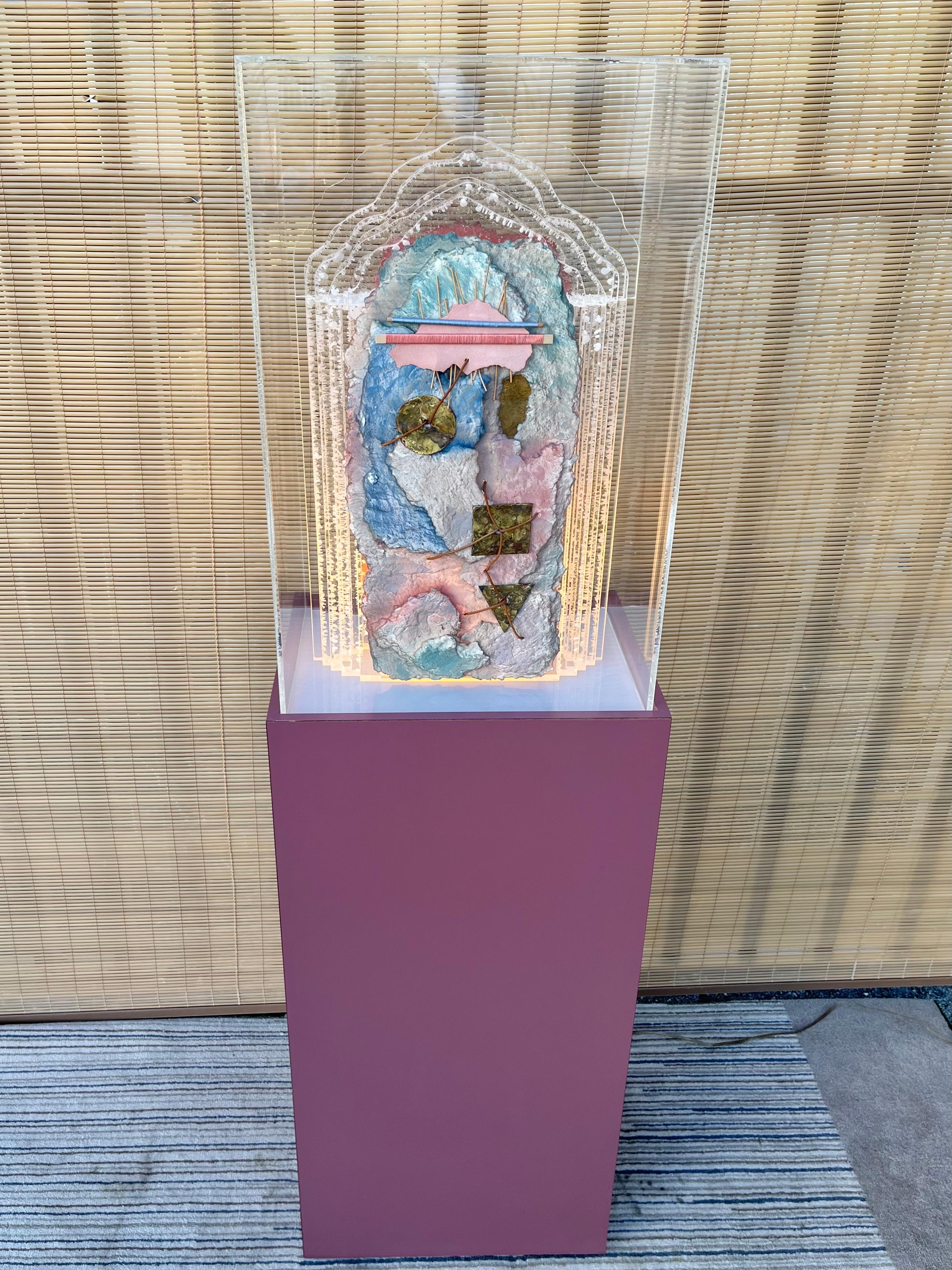 Large Postmodern Lucite and Mixed Media Light Sculpture With Pedestal and a Box Acrylic Cover. Circa 1980s. 
Features an abstract Southwestern inspired mixed-media appliqué on pastel colors, textiles, paper, and brass, over a multilayered lucite