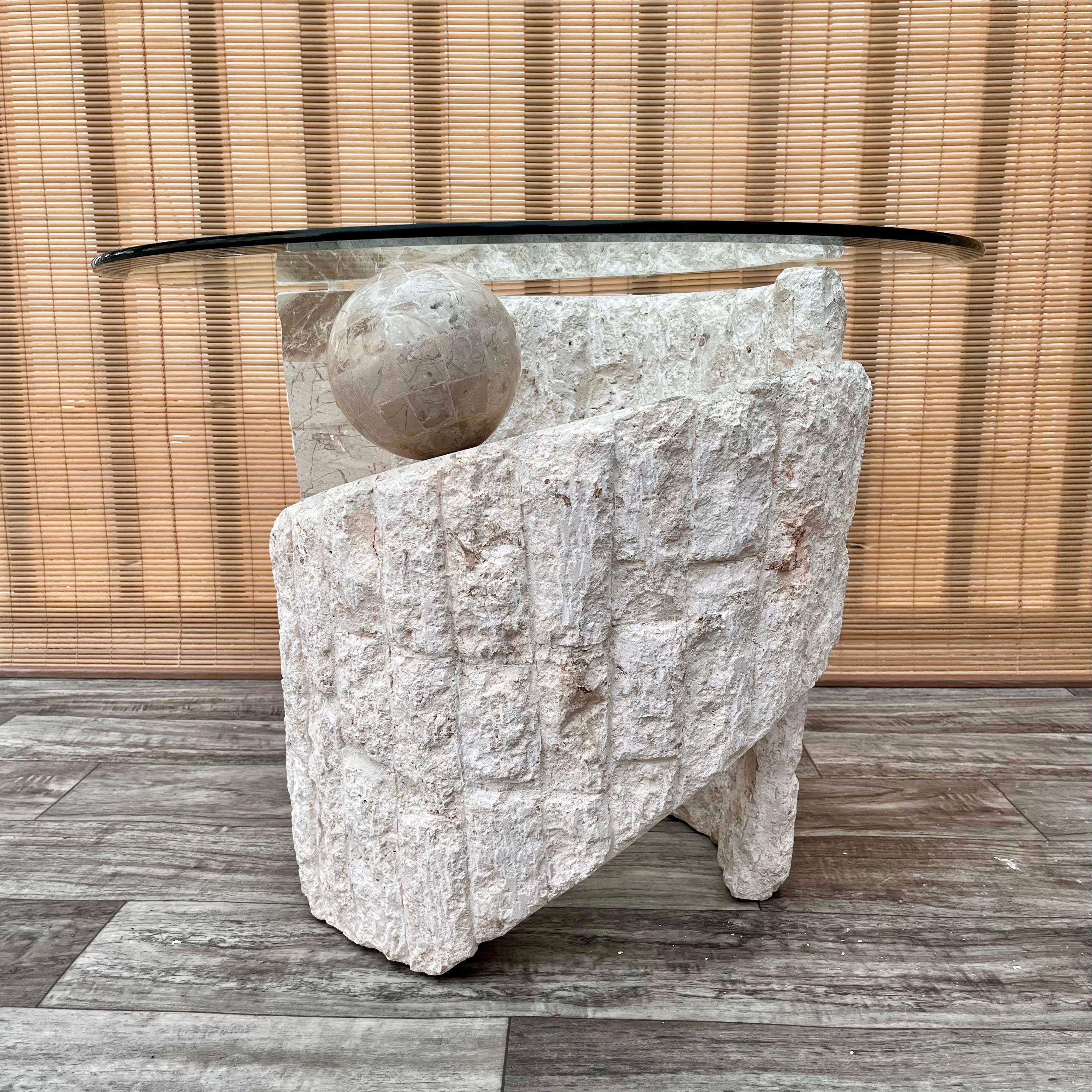 Vintage Postmodern sculptural natural mactan stone rounded accent / end table with glass top. Circa 1980s. 
Features a sculptural spiral pedestal with a contrasting combination of fractured and polished neutral color Mactan stone and topped with a