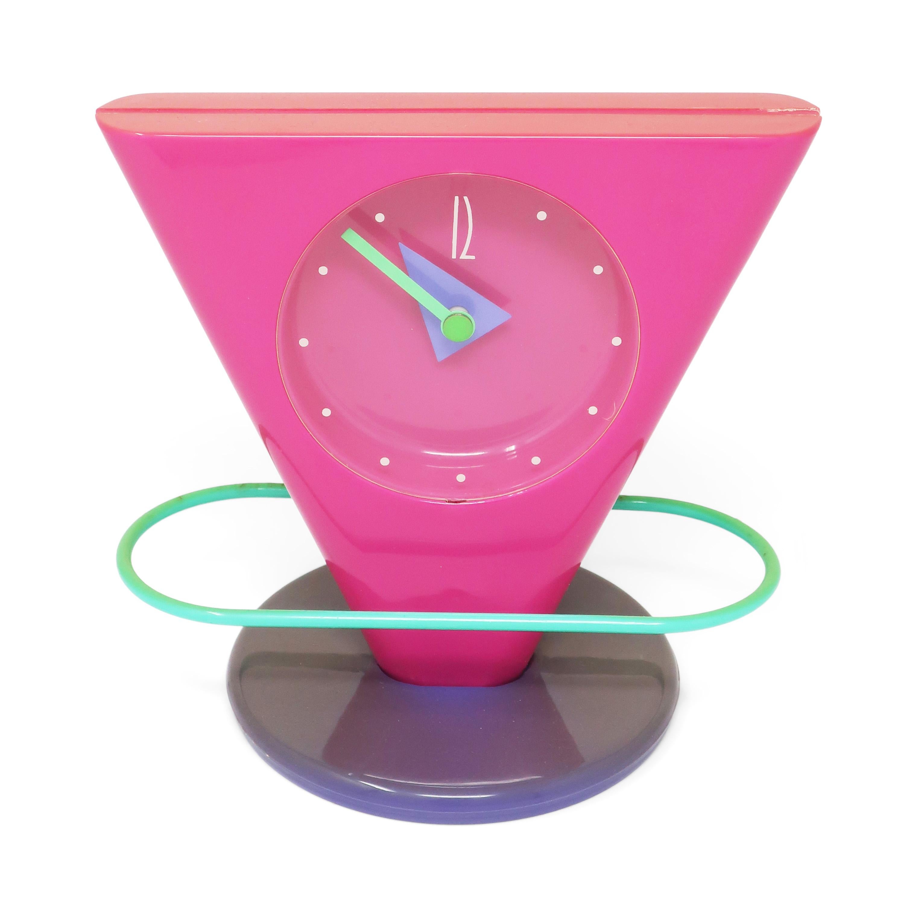 Une fantastique horloge de bureau, de cheminée ou d'étagère postmoderne avec une base ronde, un boîtier diagonal, des aiguilles géométriques et un pendule de forme ovale au-dessus de la base de l'horloge qui bat la mesure à la seconde près en