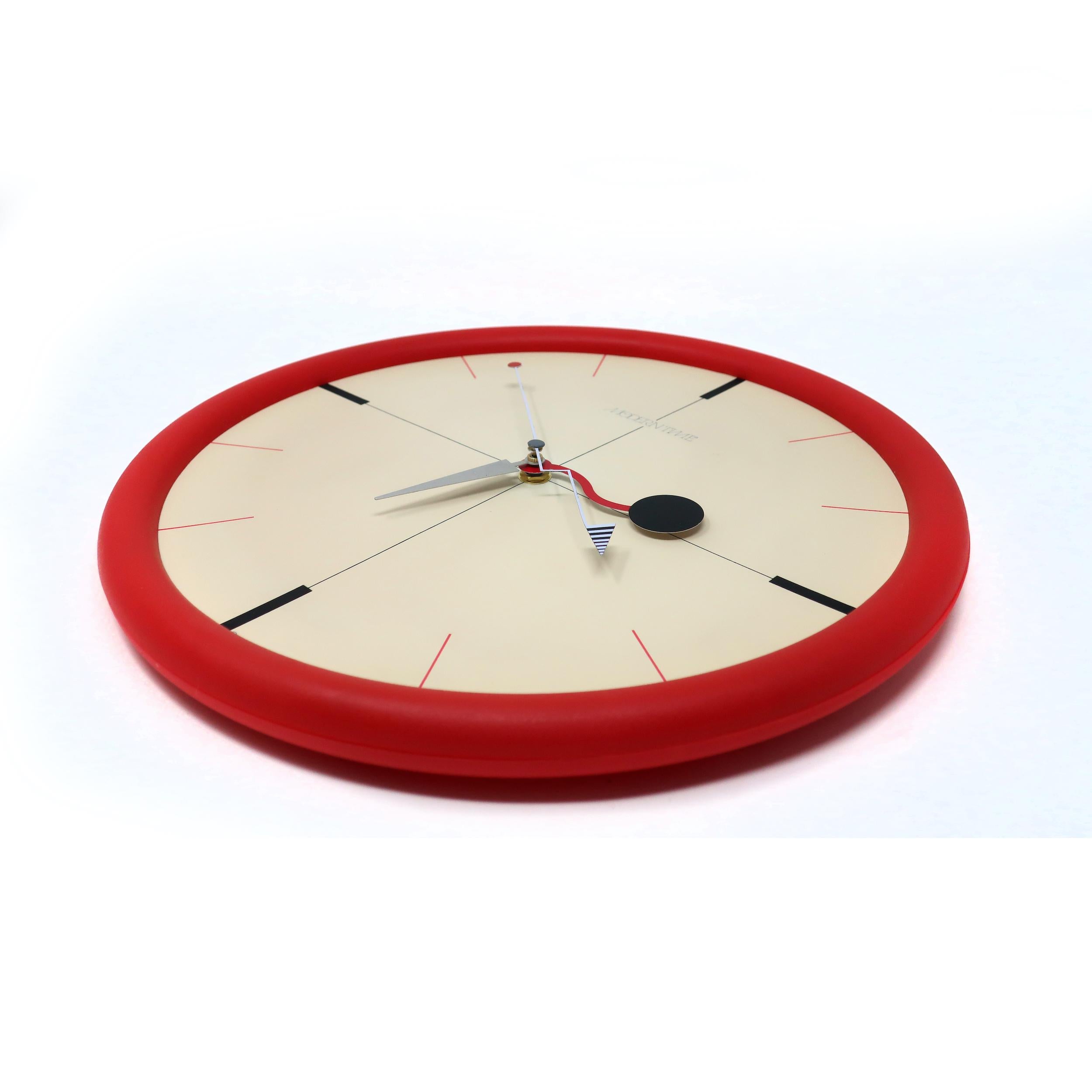A stunning postmodern wall clock with multi-color accents from Canetti's Moderntime Collection. Red plastic frame, white face, and red, black, and gray accents. It perfectly walks a line between understated & sophisticated and bright &