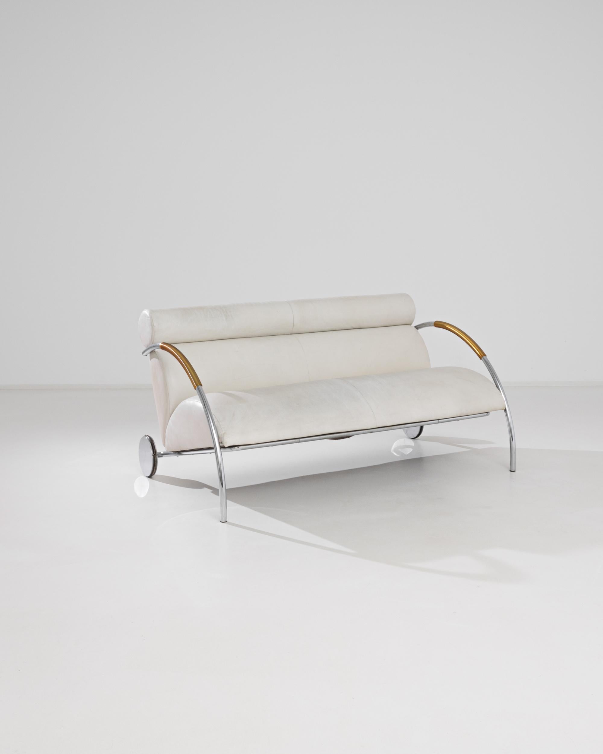 A metal sofa with upholstered seat and back designed by Peter Maly, produced in Germany circa 1980. An expanse of white leather stretches across plush cushions that appear as stacked semicircles crowned by a cylindrical headrest, flanked by swooping