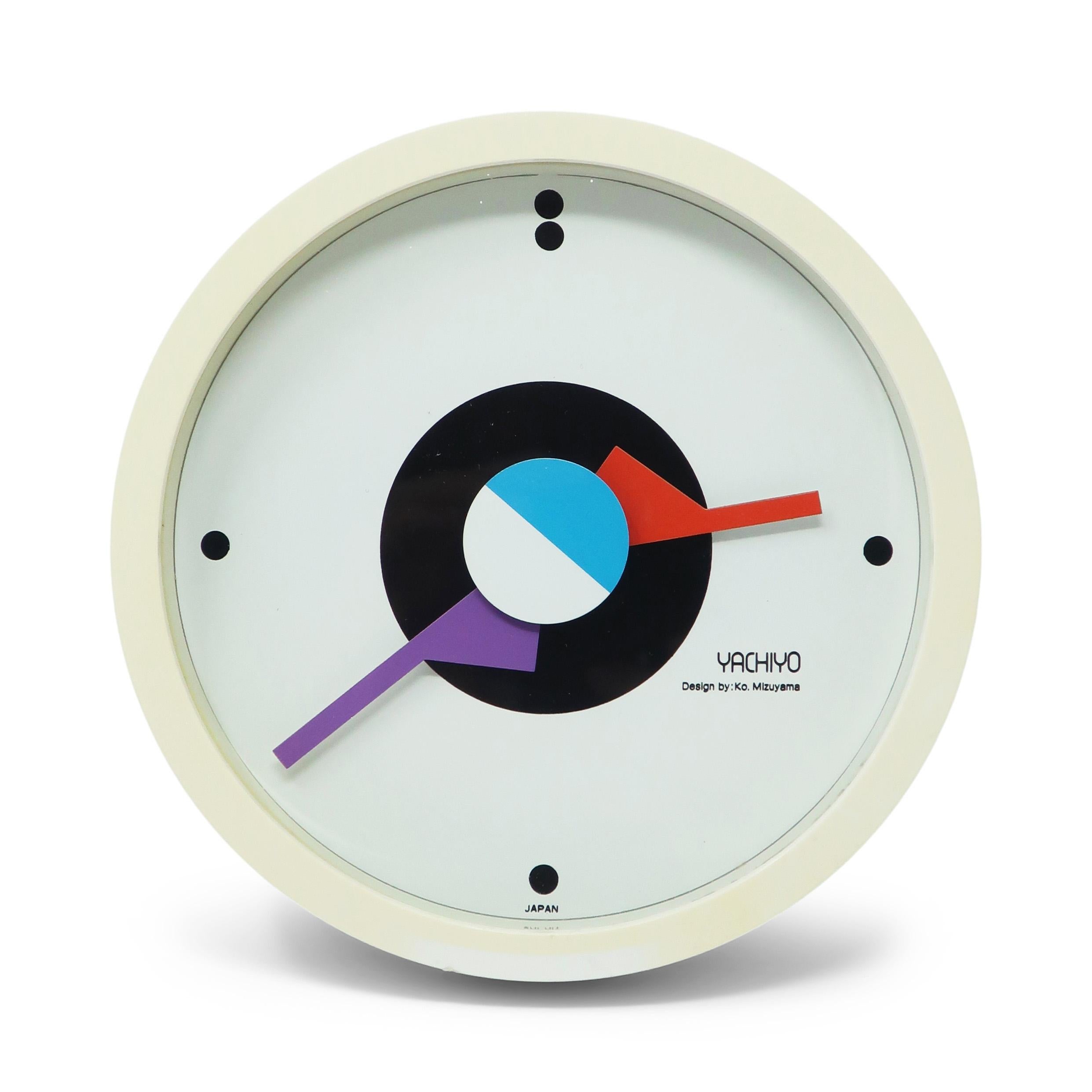 An outstanding round postmodern wall clock designed by Ko Mizuyama, a prolific Japanese designer of clocks in the 1980s.  It has a white plastic case, white face with dots for numbers, and graphical red, purple, white, and blue hands.

In good
