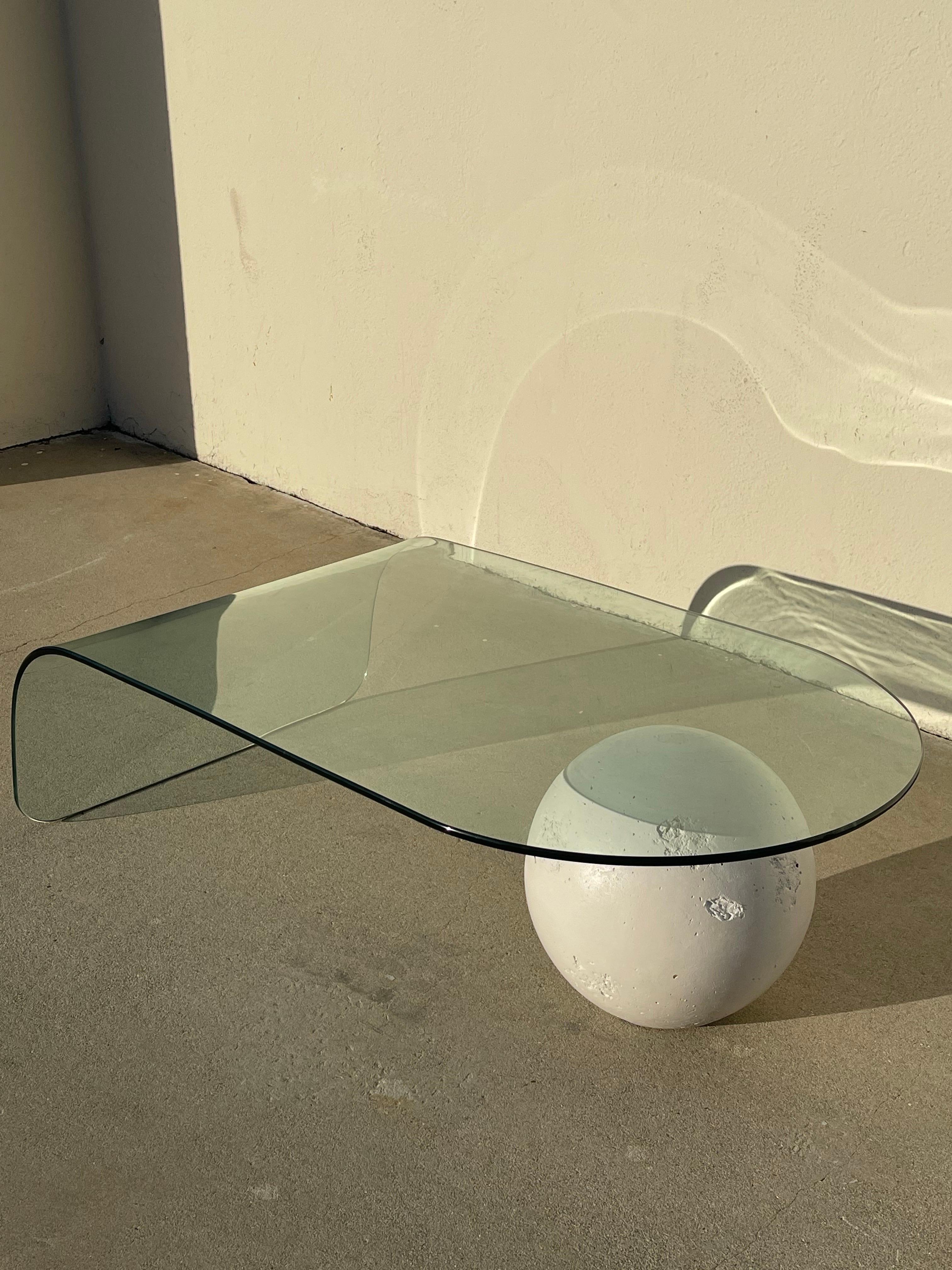 Glass coffee table with a waterfall edge and plaster ball. Origin: USA circa 1980’s. In excellent condition with minor wear consistent with age and use.