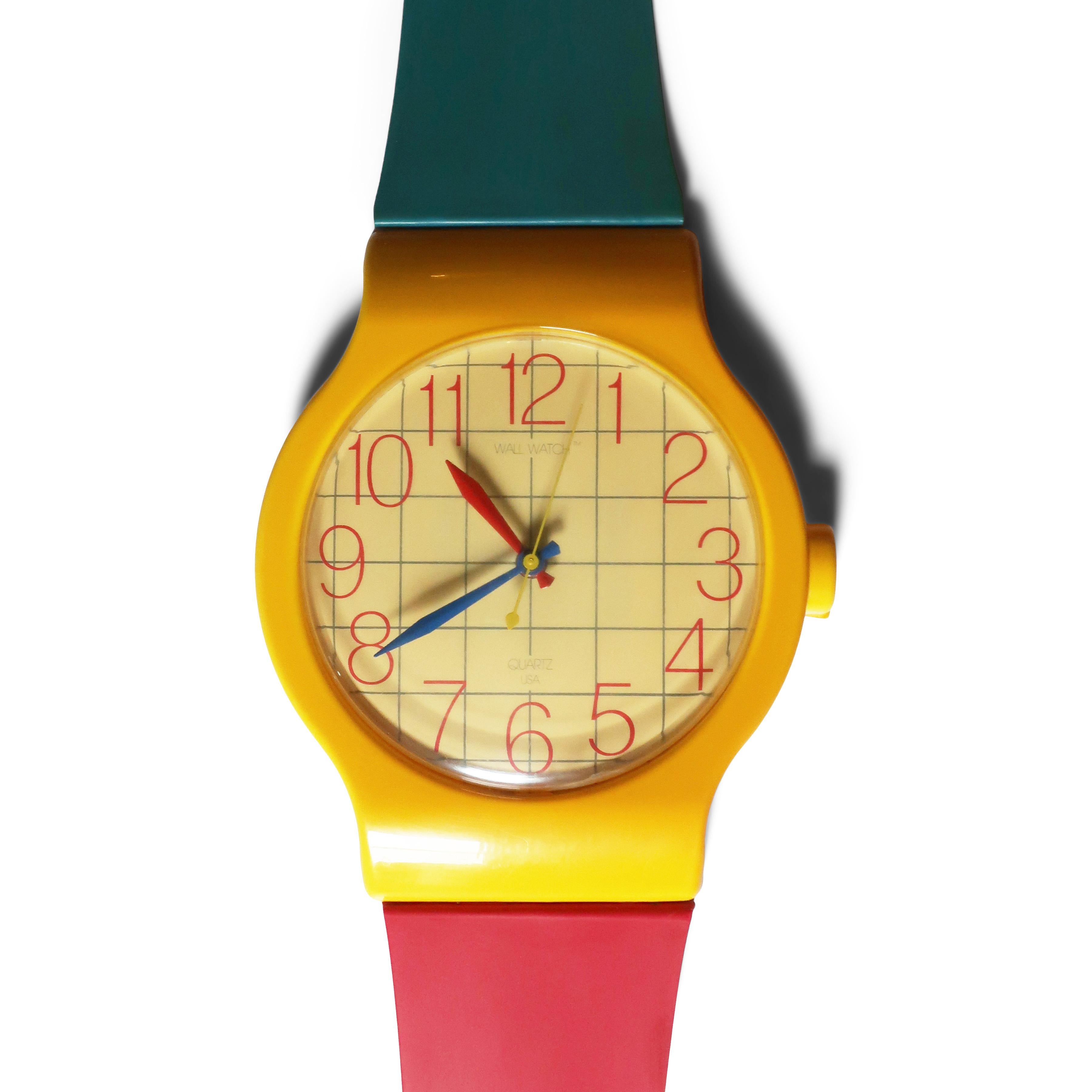 A fantastic vintage 1980s wrist watch wall clock, in the vein of Swatch's great designs.  With a red and blue band, yellow bezel, red numbers and grid on a light yellow pink face, and red and blue hands, this is a stunner! 

In good vintage