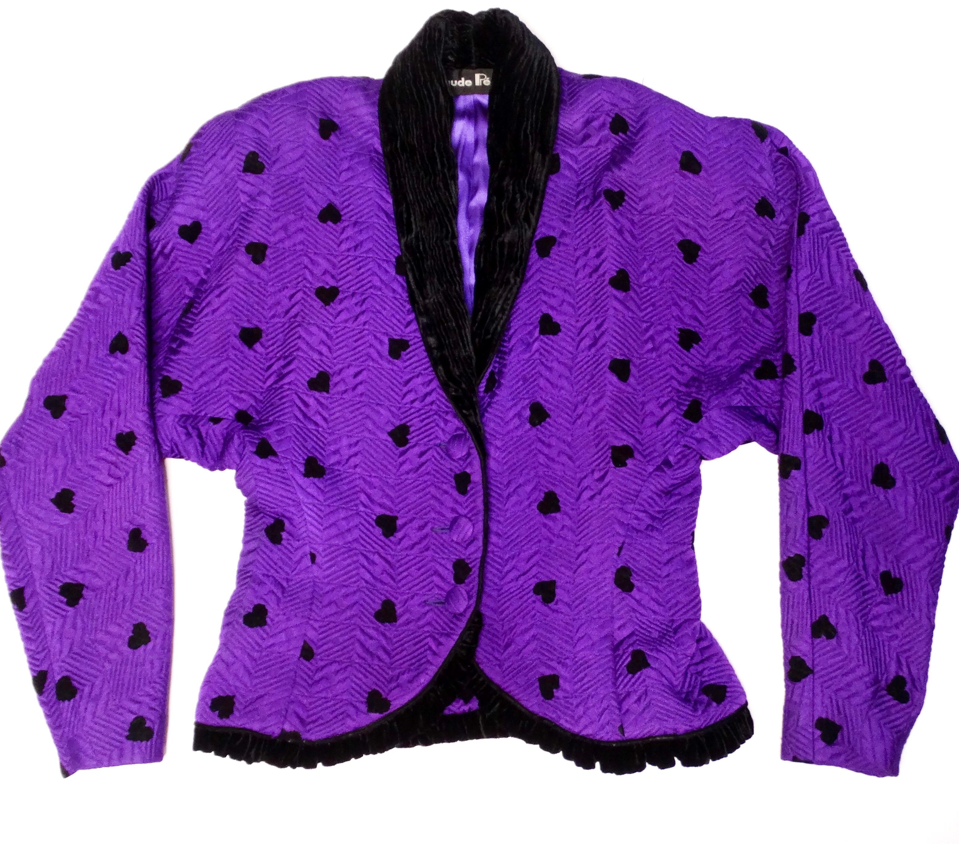 Step into a world of playful elegance with this fabulous 1980s Purple & Black Hearts Blazer and Pencil Skirt Suit Set. The entire ensemble showcases a vibrant purple fabric adorned with striking black hearts, perfect for making a whimsical