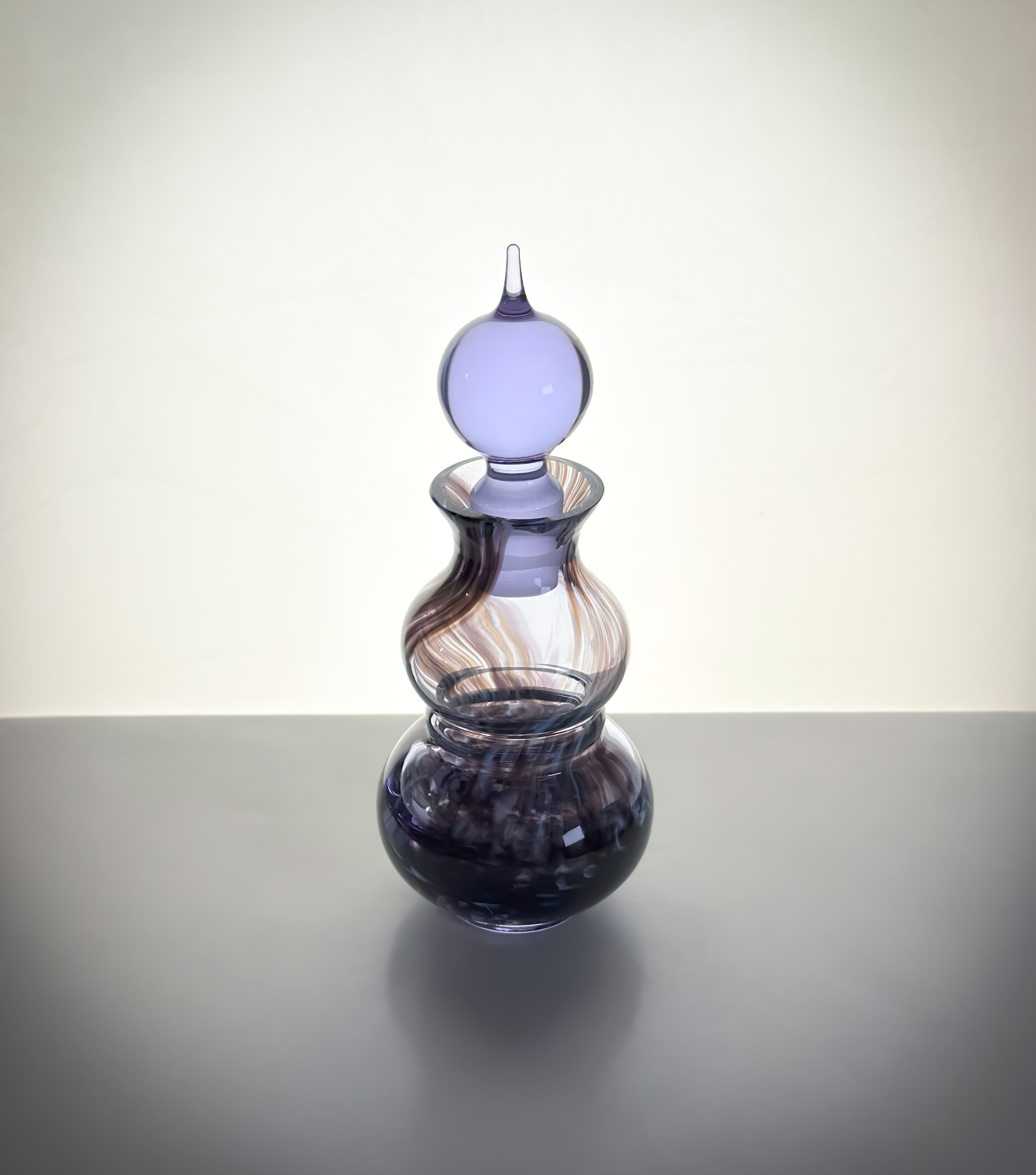 Una bottiglia di profumo in vetro artistico con tappo in vetro, realizzata alla fine degli anni '80 dai famosi vetrai scozzesi Caithness. 

Questo pezzo da collezione, chiamato Jasmine, è stato disegnato da Colin Terris, meglio conosciuto per i suoi