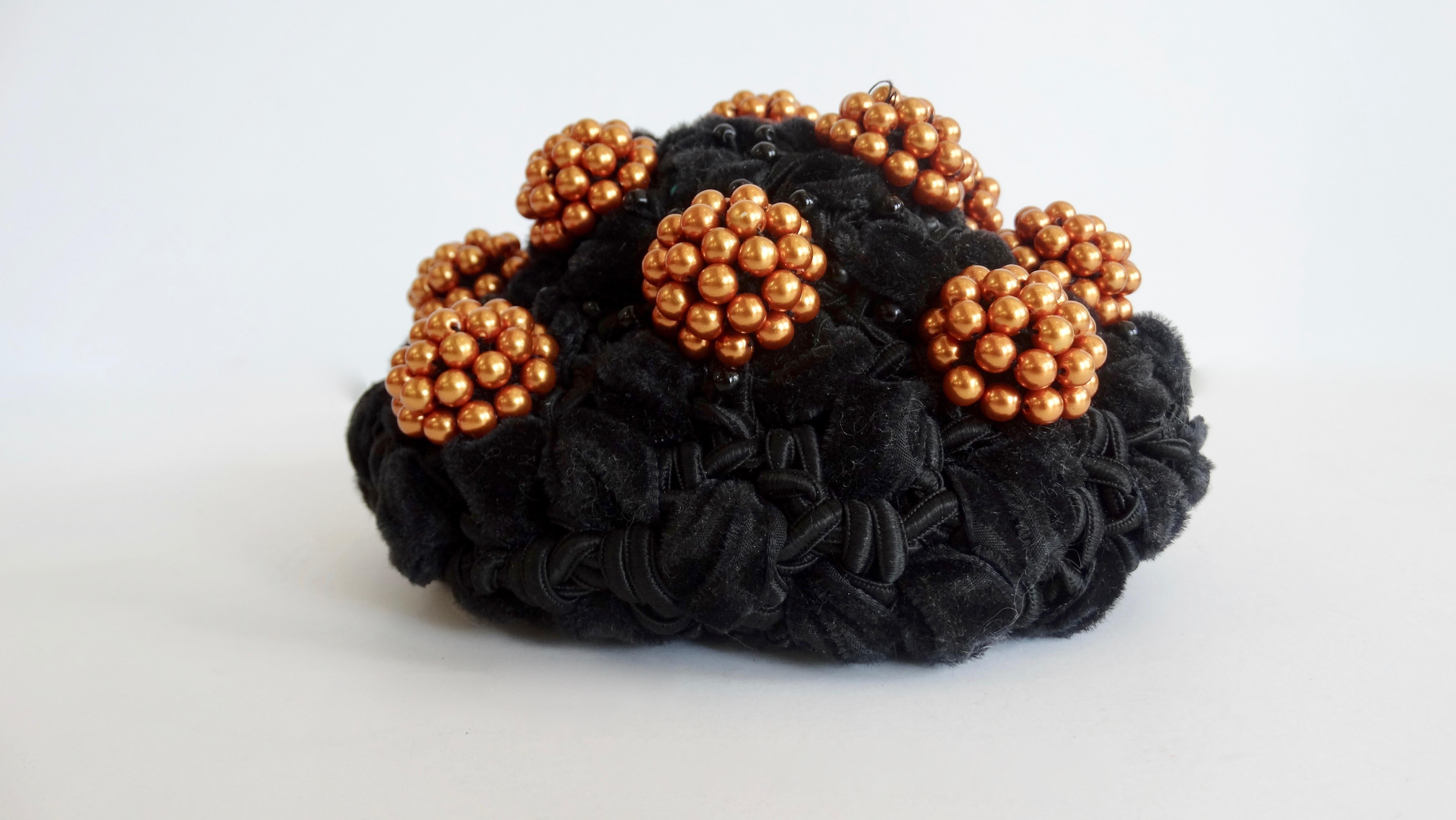 Elevate your headwear with this adorable bun cover! Circa 1980s, this Isabel Canovas bun cover is made of intertwined black fabrics and is embellished with copper colored bead clusters. Small black beads are scattered throughout for a subtle accent.