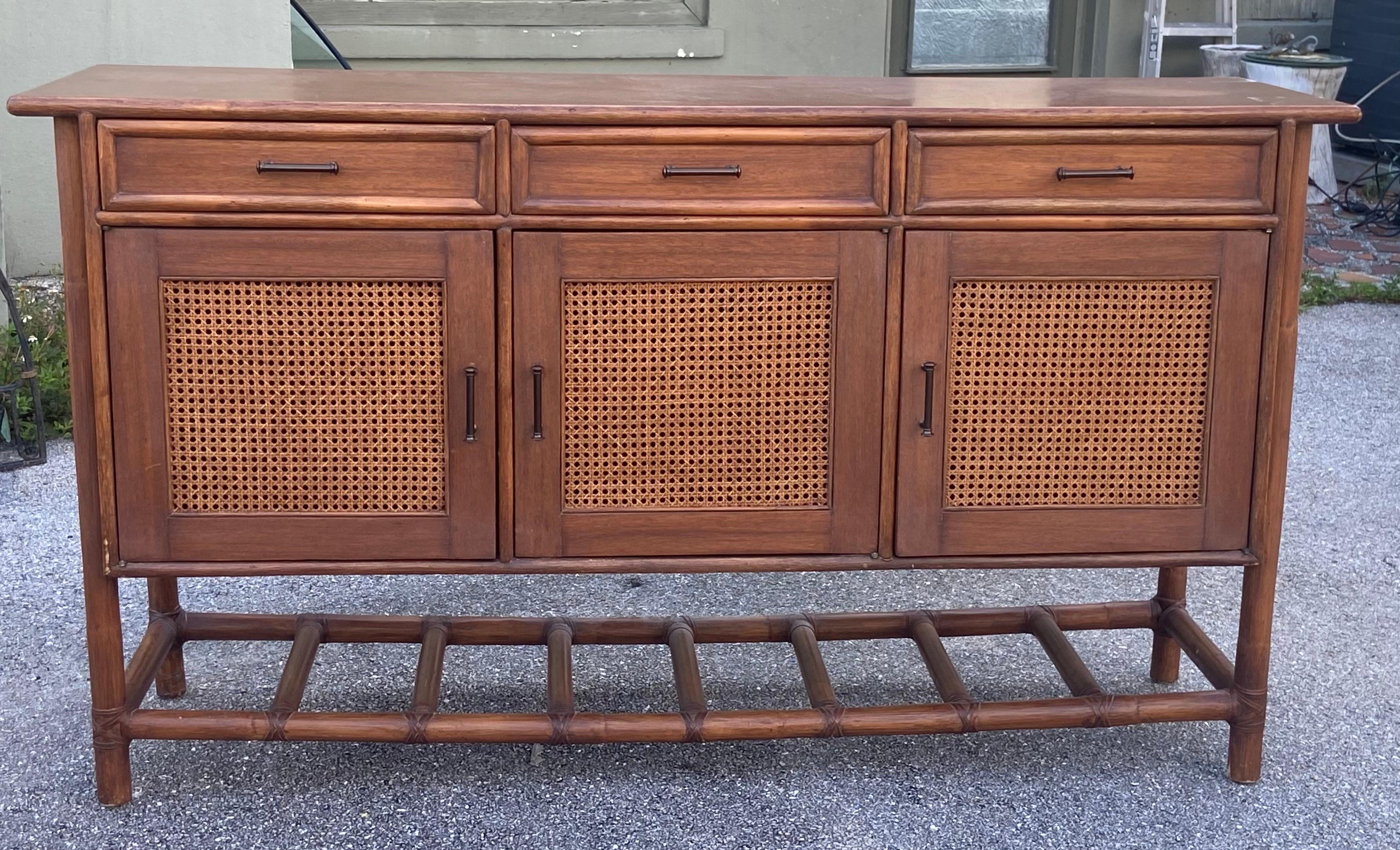 Credenza vintage in rattan degli anni '80, con dimensioni di 66 pollici di larghezza, 18,5 pollici di profondità e 37,5 pollici di altezza. Questo mobile è dotato di tre cassetti e tre armadietti che offrono un ampio spazio di archiviazione. La