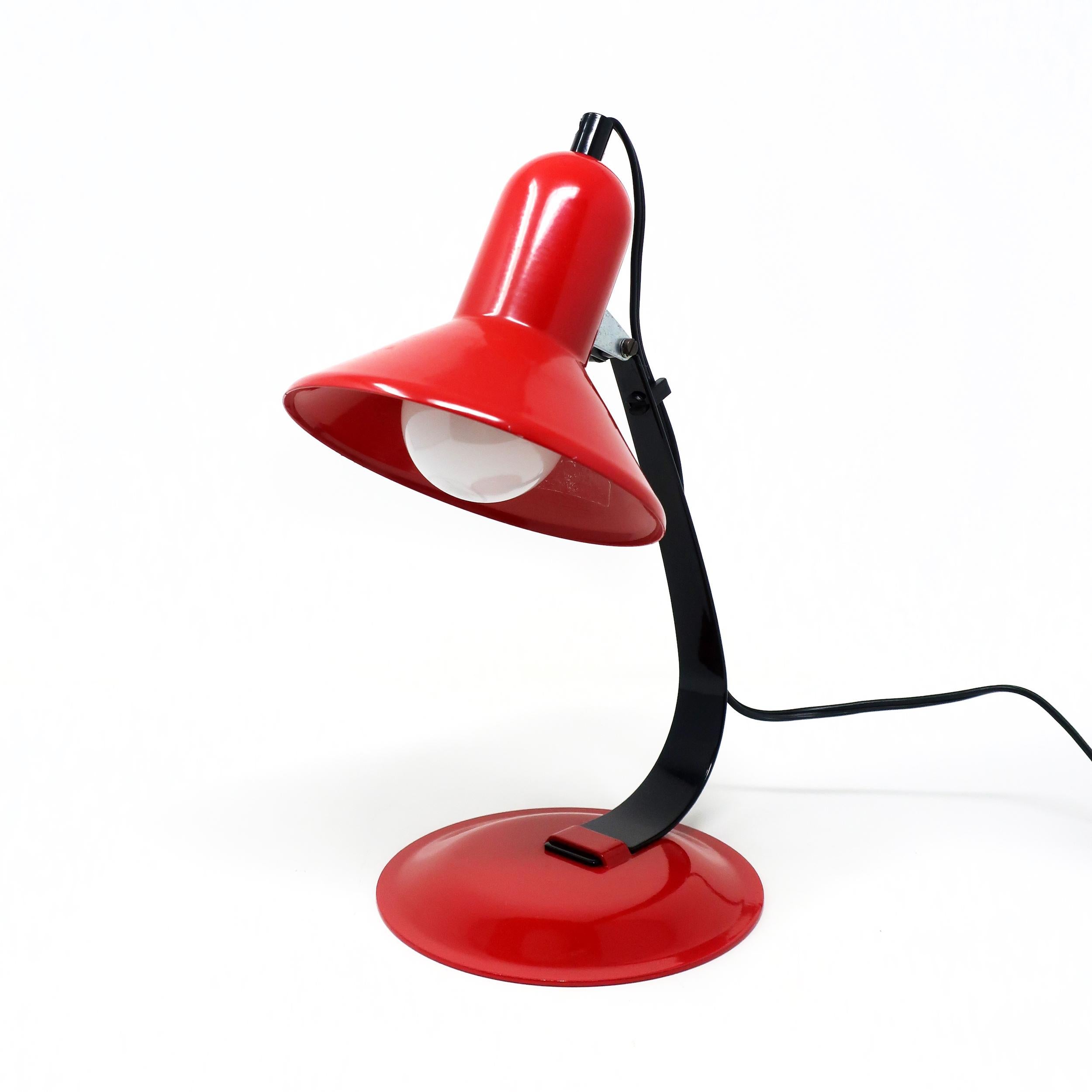 Perfectly straddling the line between mid-century modernism and postmodernism, this desk lamp has red enameled metal base and shade, black metal stem, and a black cord with on/off switch and cord clip. It has beautiful lines and a sensuous