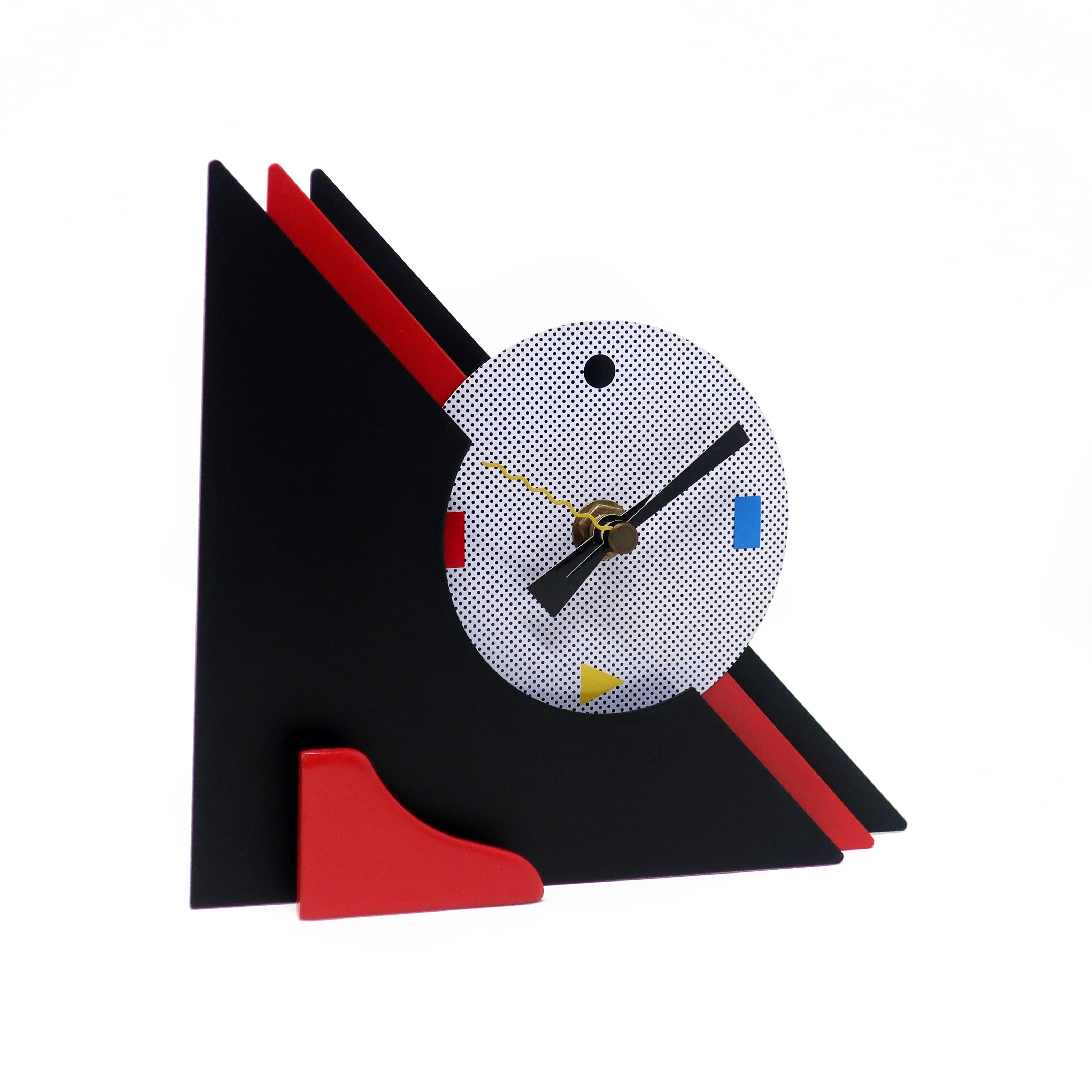 With a stunning combination of red and black enameled metal, red lucite accents, and primary colored shapes at 3, 6, and 9, this postmodern clock is designed with a stacked triangular design that gives it a rare and beautiful three dimensionality.
