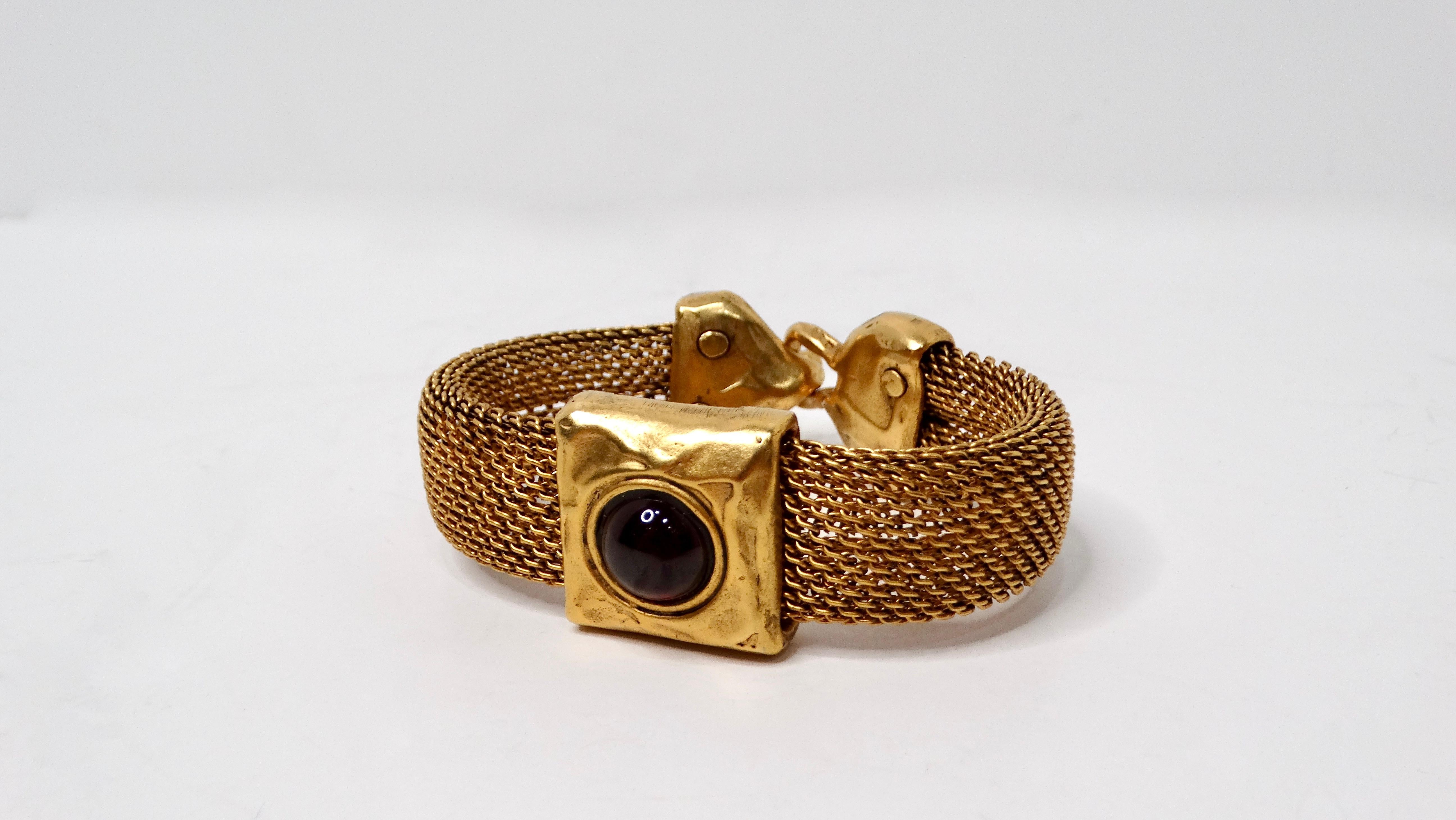 Esta impresionante pulsera de malla de granate con cabujón rojo y tono dorado de los años 80 es una llamativa pieza de joyería vintage que destila elegancia y sofisticación. La pieza central de la pulsera presenta una vibrante piedra cabujón roja,