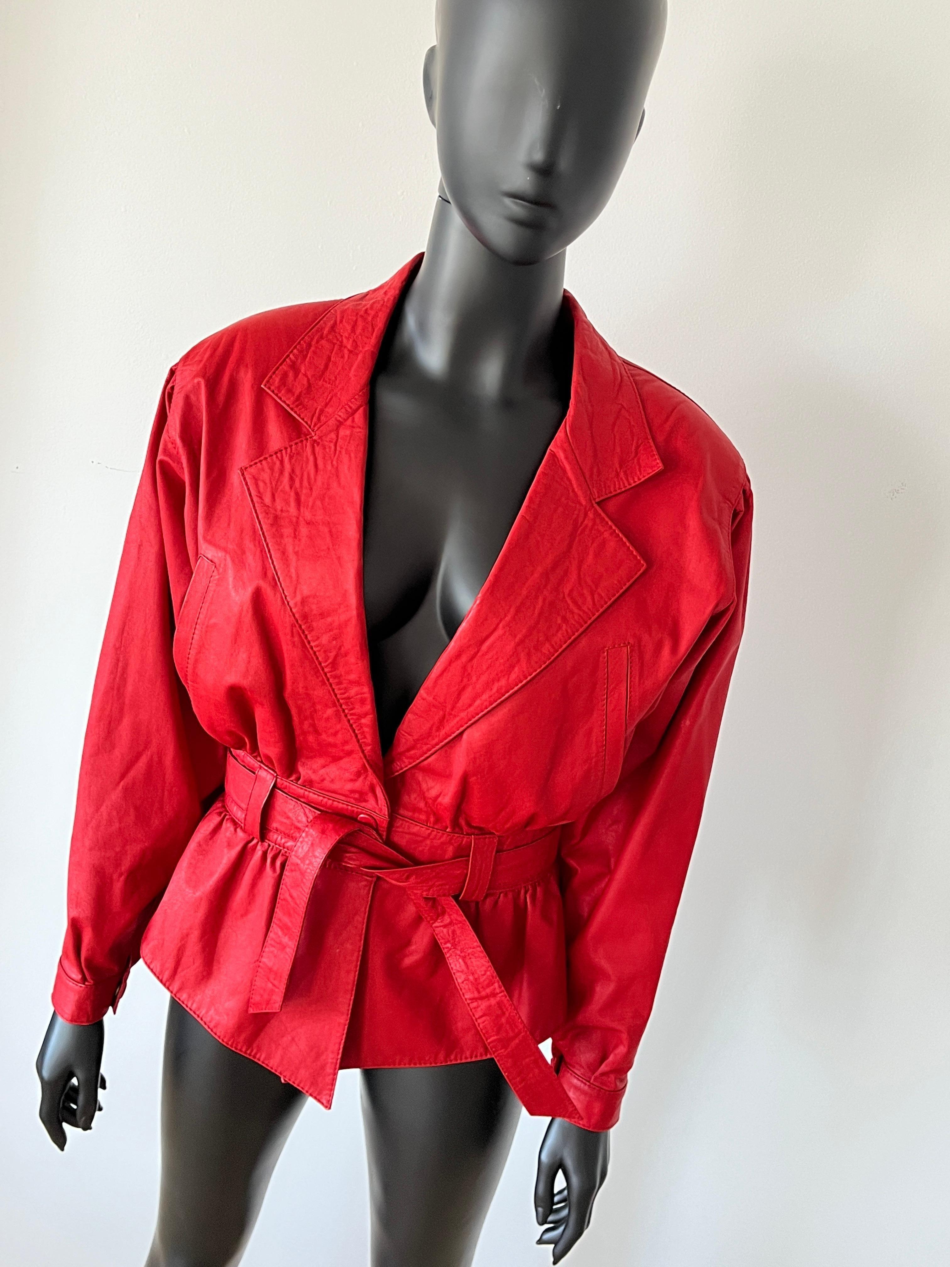 La veste en cuir rouge des années 1980 présente des manches bouffantes, une taille cintrée avec ceinture et une fermeture à pression. 
En très bon état vintage, entièrement doublé. 