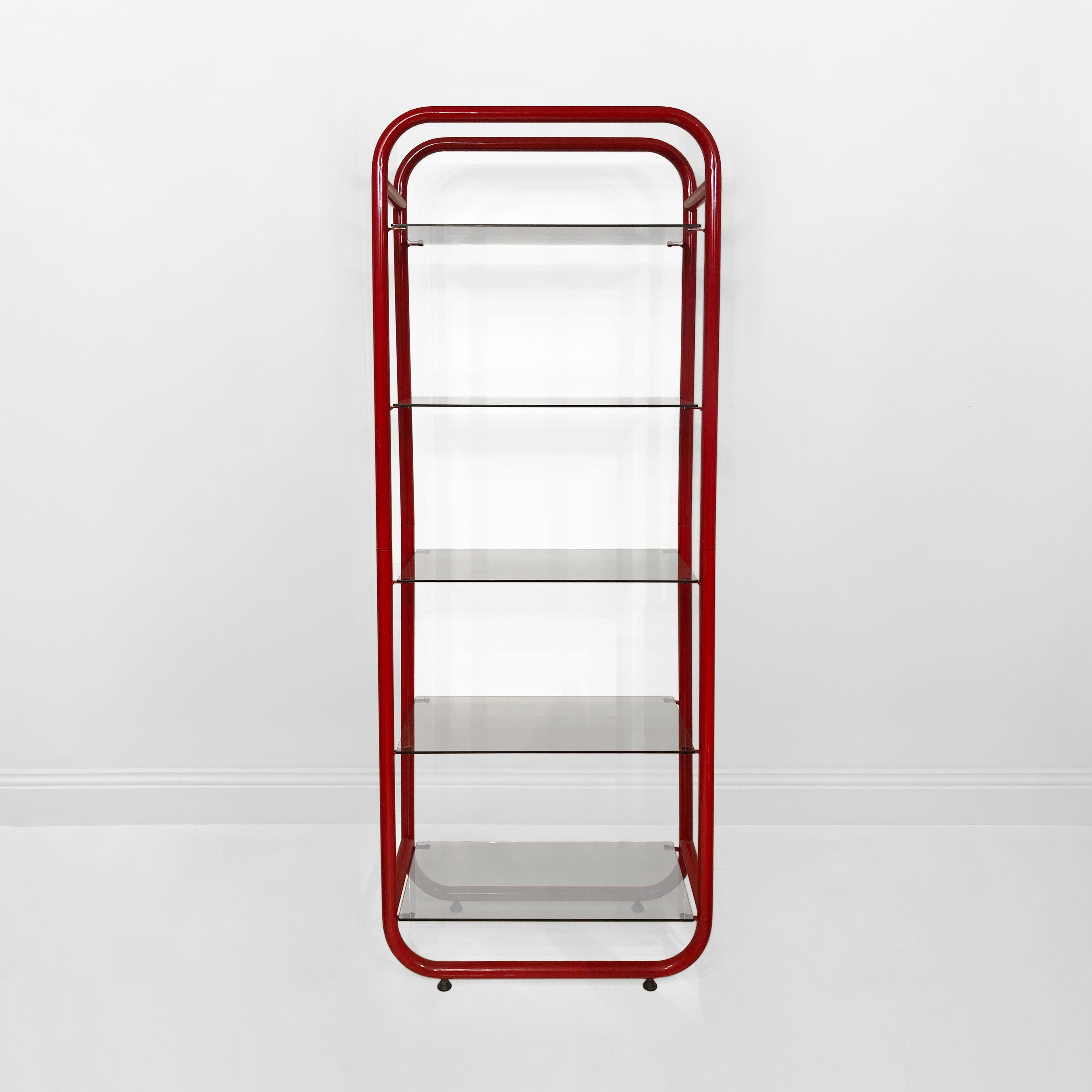 Red Italian etagere, very much in the manner of the Memphis Milano group, and originating from the 1980s. A tubular, powder-coated metal frame in a pleasing vermillion houses five clear glass shelves. One of the shelves has a small chip.

This fun