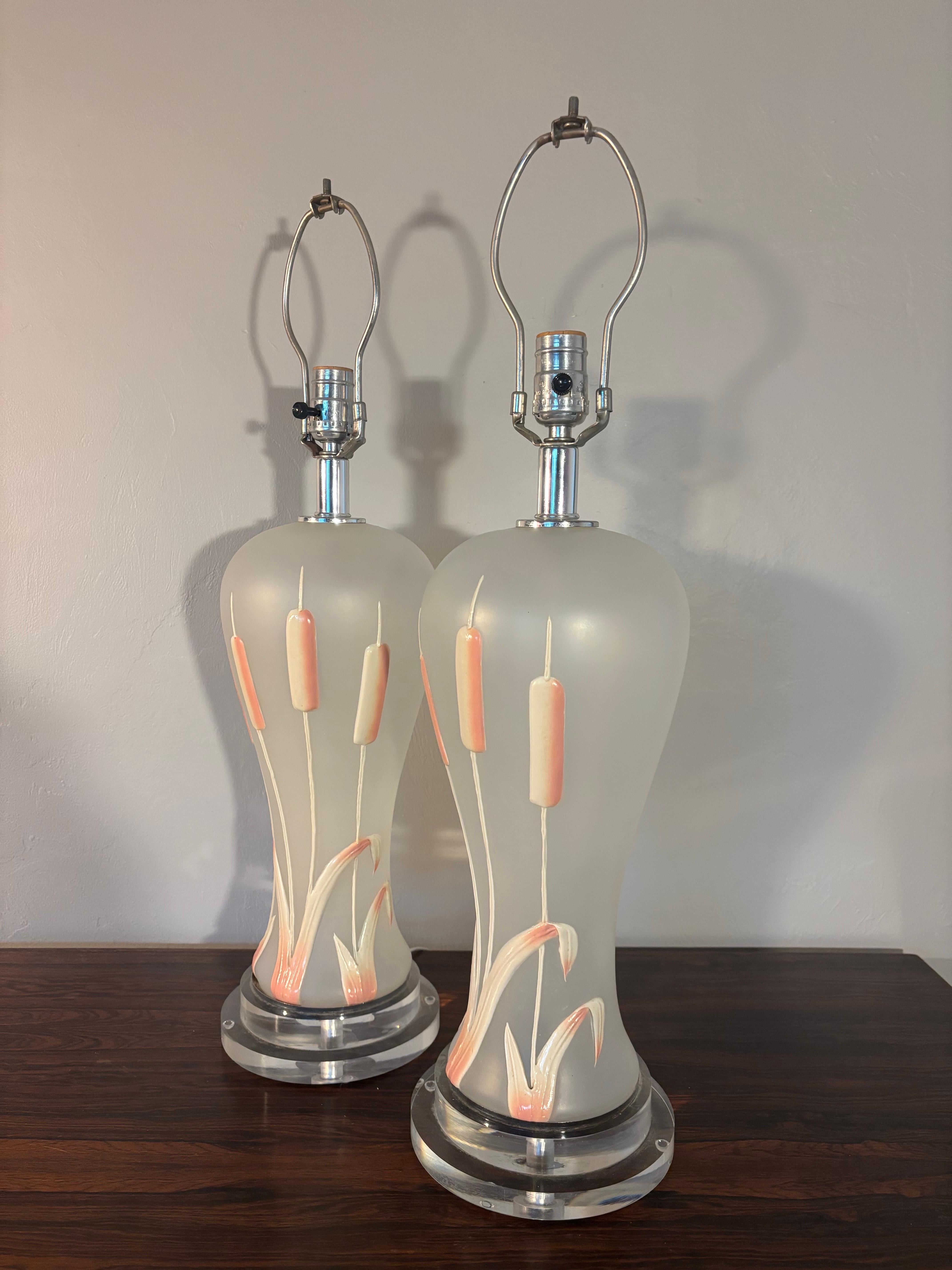 Pair of vintage frosted glass and lucite table lamps. 

Featuring a white and blush pink cattail motif. 

Hollywood regency in style 

Sold without shades. 

22” tall with out harp
7” deep
7” wide
