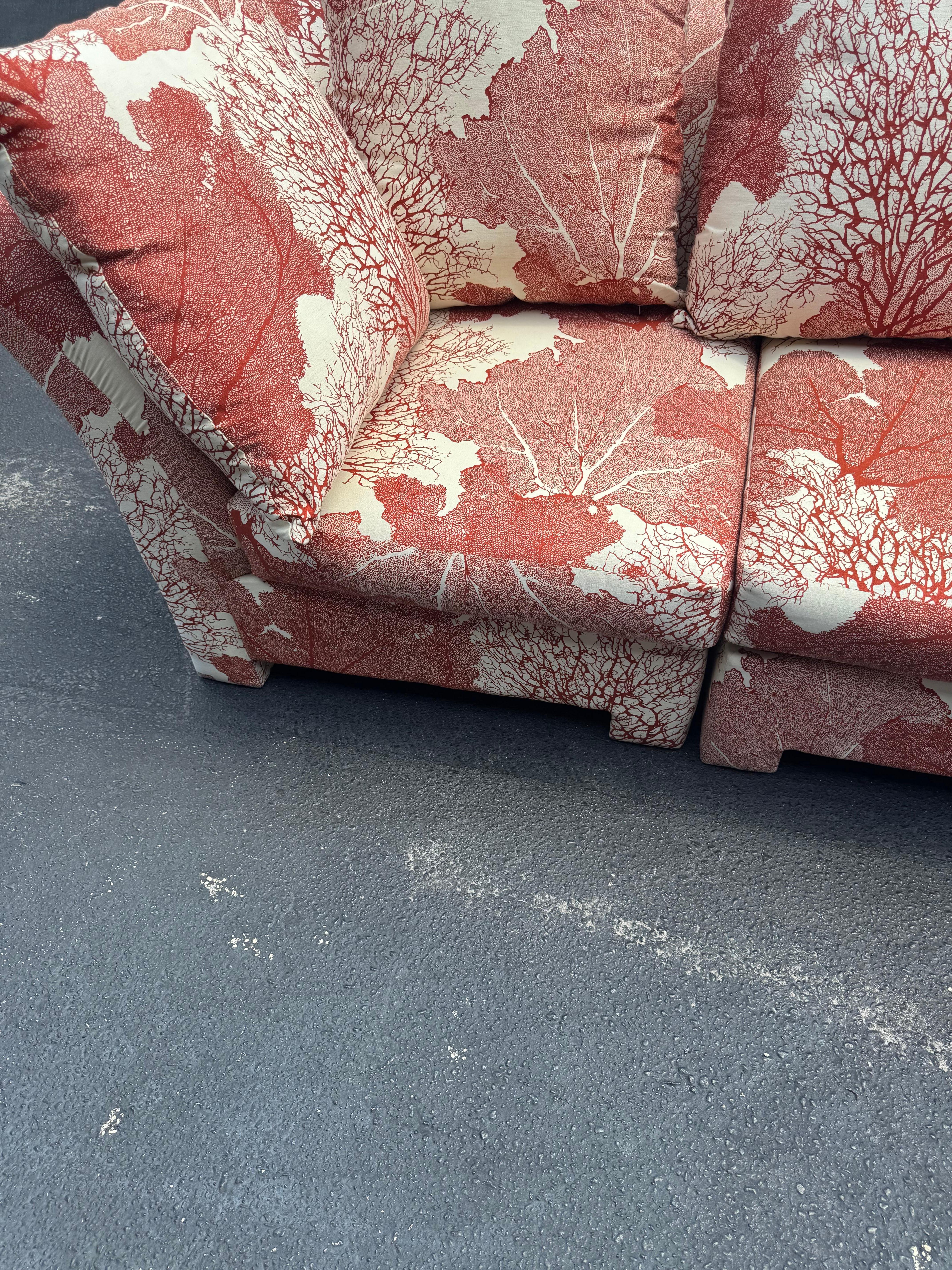 This fabulous sofa has been recently recovered . The soft white background is the base for assorted coral motif impressions in a vibrant coral color. It can be configured in other configurations as well. The ottoman is included. 