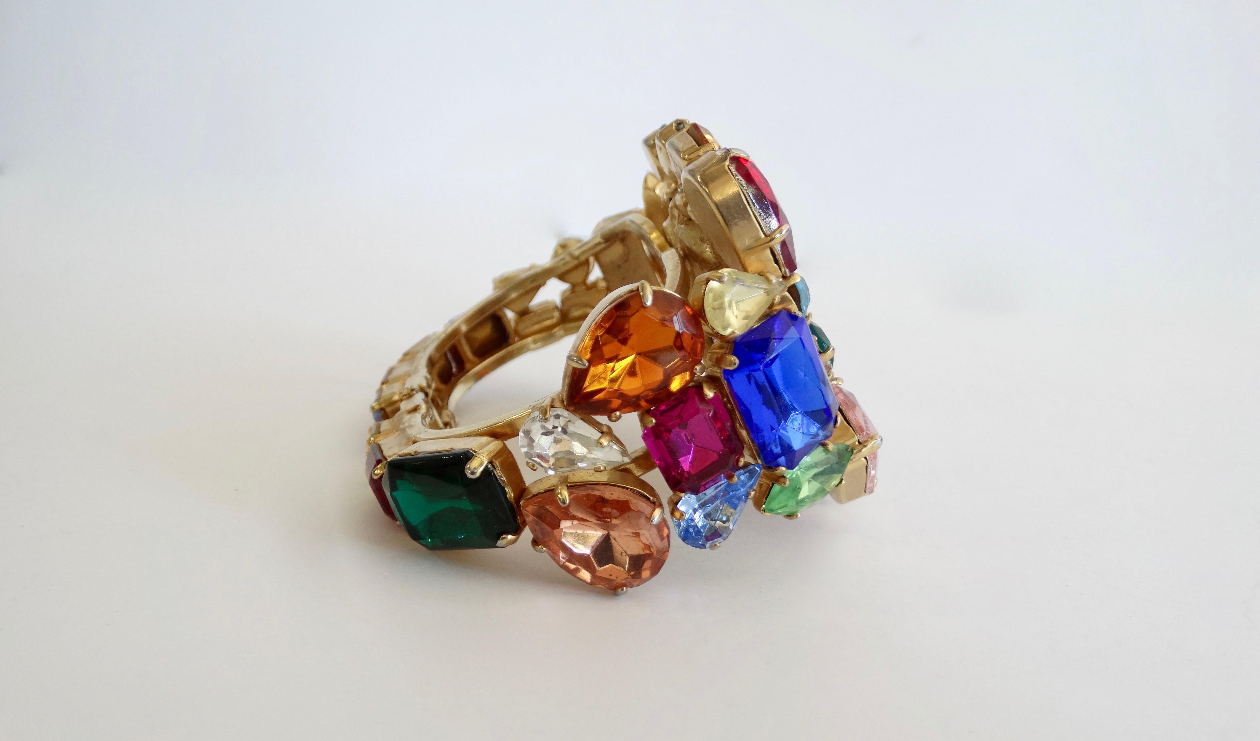 Wear your heart on your wrist with this amazing heart cuff! Circa 1980s, this unsigned cuff is embellished with various sizes and colors of rhinestones. Features a large rhinestone heart in the center and an easy clamp closure. Reminiscent of past