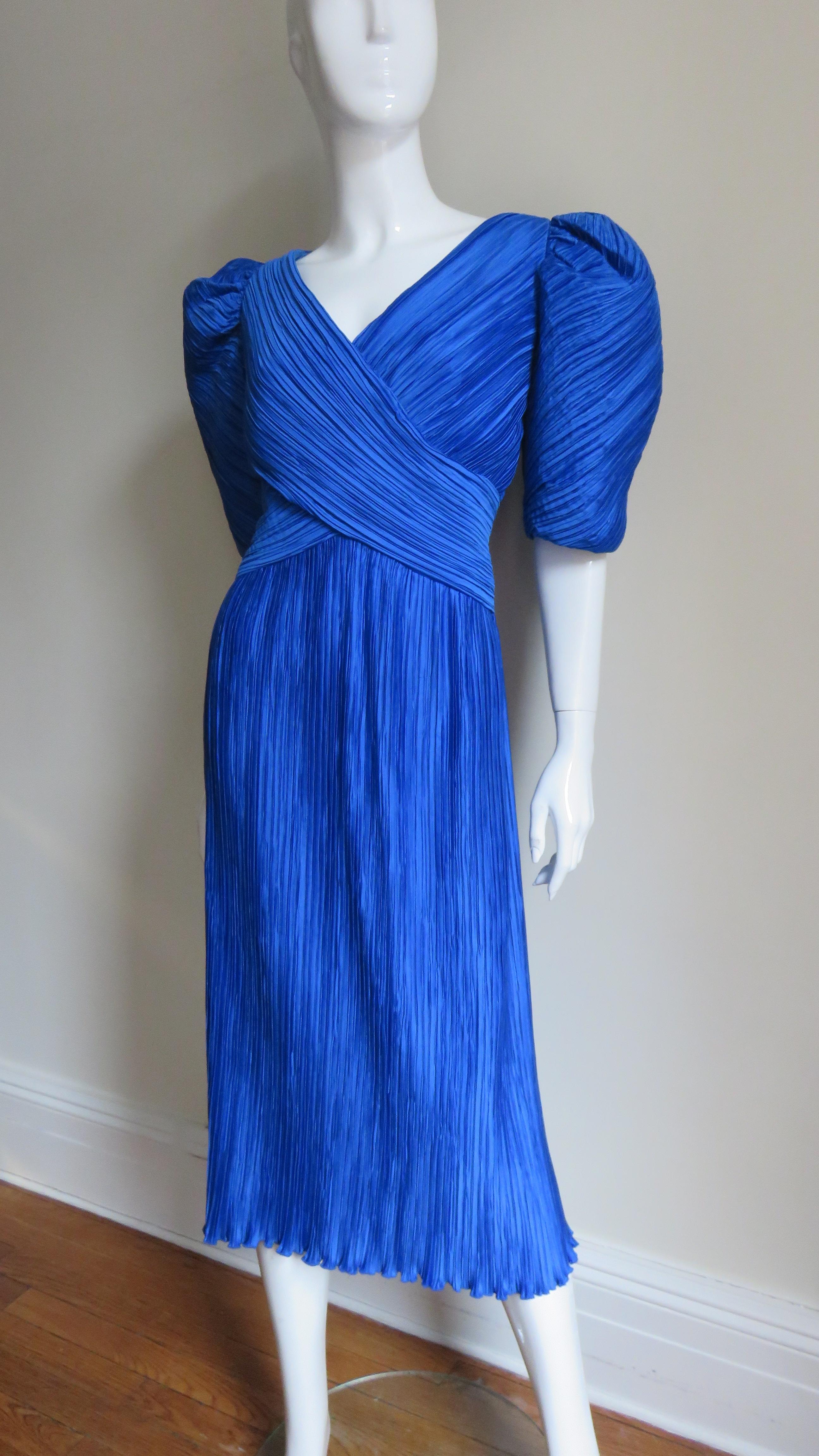 A great dress in cobalt blue micro pleating from Richilene, New York.  It has faux wrap V front neckline with elbow length puff sleeves and a straight skirt.  The bodice is lined in matching blue and it has a center back zipper.  
Fits sizes Small,
