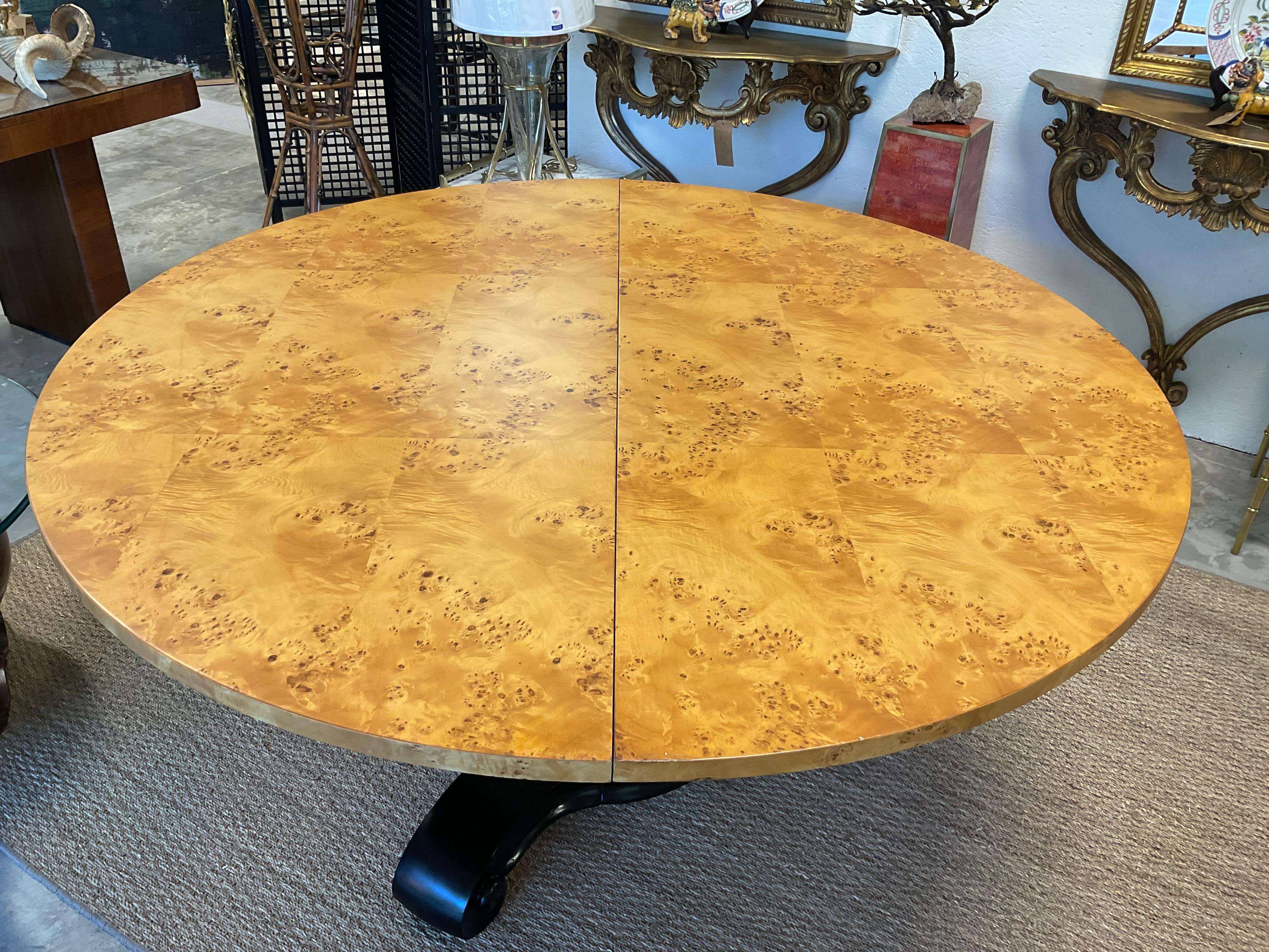 Lovely ,round dining table with the simplicity of Biedermeier style. 5 foot round ,  burl veneer top with a black accented, tri-leg base.  1980s, American made, which could be used as a large center table, also. No leaves present. 