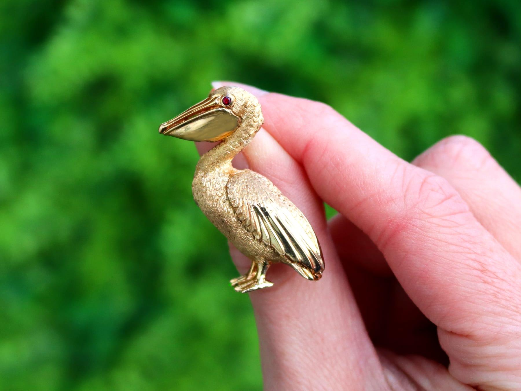 An impressive vintage 1980s 0.03 carat ruby and 14 karat yellow gold 'pelican' brooch by Dankner; part of our diverse gemstone jewelry and estate jewelry collections.

This fine and impressive vintage brooch has been crafted in 14k yellow gold.

The