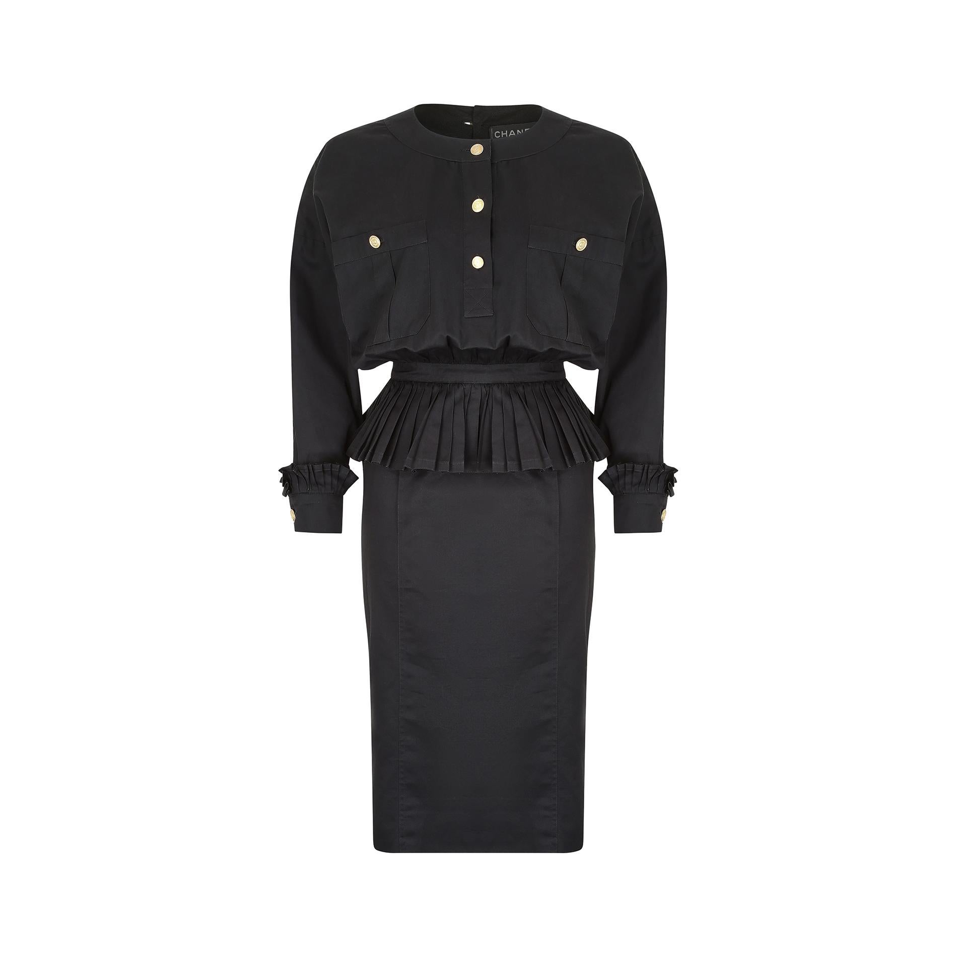 This Chanel black cotton dress is an amazing example of the fashion house's expert tailoring, and of the structured styles of the 1980s. It has a high rounded neckline, sloped, dropped seam shoulders and fastens down the back of the bodice with four