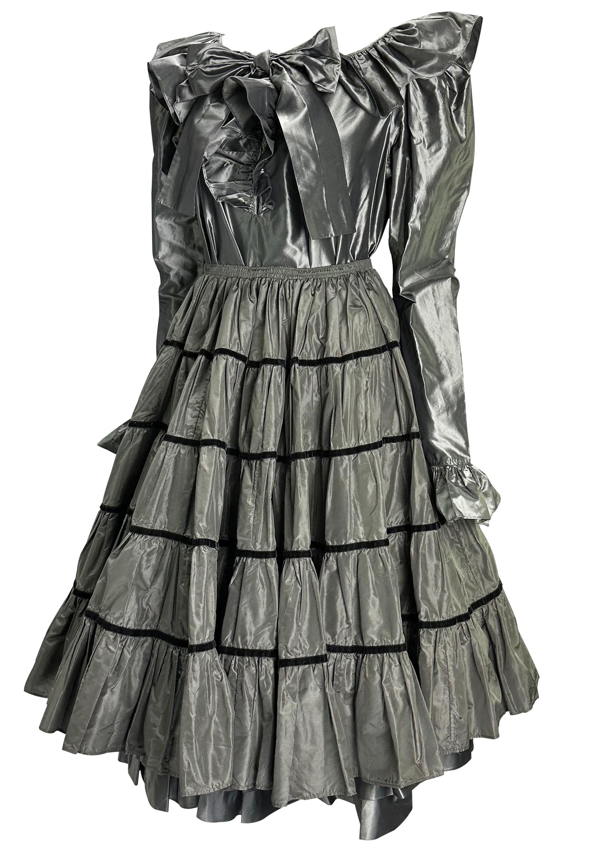 Presenting a gorgeous silver Saint Laurent Rive Gauche three-piece skirt set, designed by Yves Saint Laurent. From the 1980s, this incredible set is made up of three pieces - a silk top, a ruffled underskirt, and a velvet-trimmed exterior skirt. The