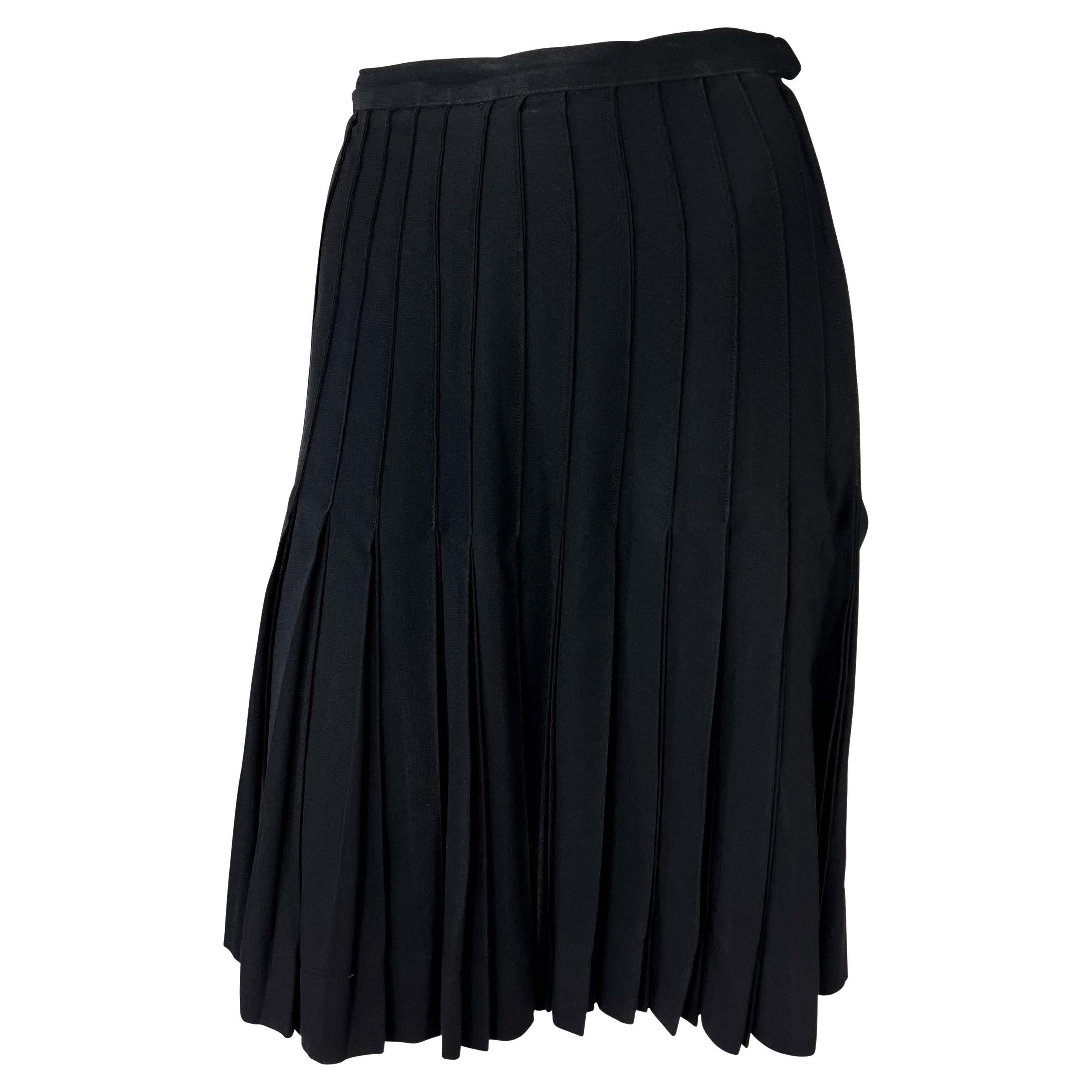 Présentation d'une jupe noire plissée en accordéon conçue par Yves Saint Laurent pour sa ligne de prêt-à-porter, Saint Laurent Rive Gauche, dans les années 1980. Les plis sont cousus de manière experte pour créer des lignes contrôlées de la ceinture