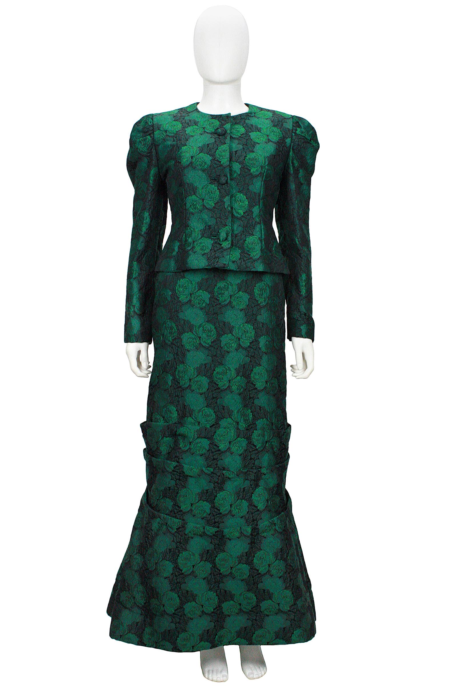 Scaasi off the shoulder gown
Green and black floral brocade 
Inner boning and lining 
Inner tulle to give the skirt fullness 
Pleat and bow skirt detail 
Fitted jacket with button closures 
