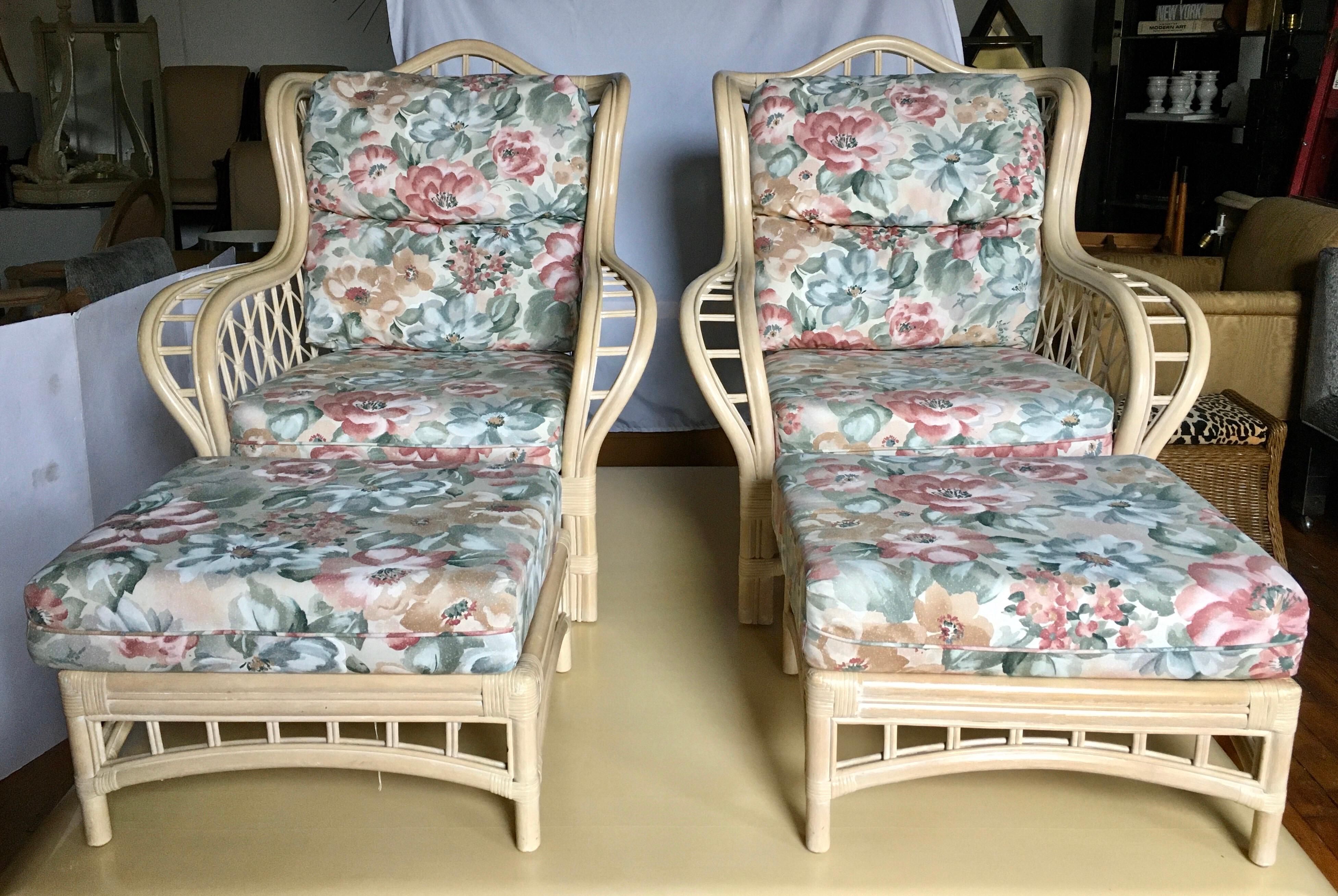 Pair of rattan faux bamboo wing chairs and ottomans by Lane. These large sculptural curved lounge chairs have original removable seat and back floral print cushions which can easily be reupholstered. Pair of ottomans also have original removable