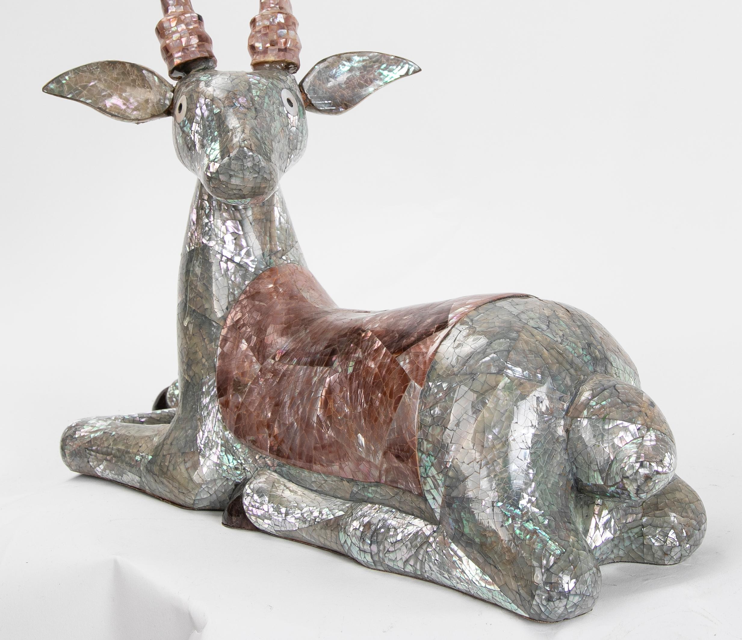 Skulptur einer Hirsche aus den 1980er Jahren, die mit Perlmuttgeflecht auf dem Boden liegt.
 