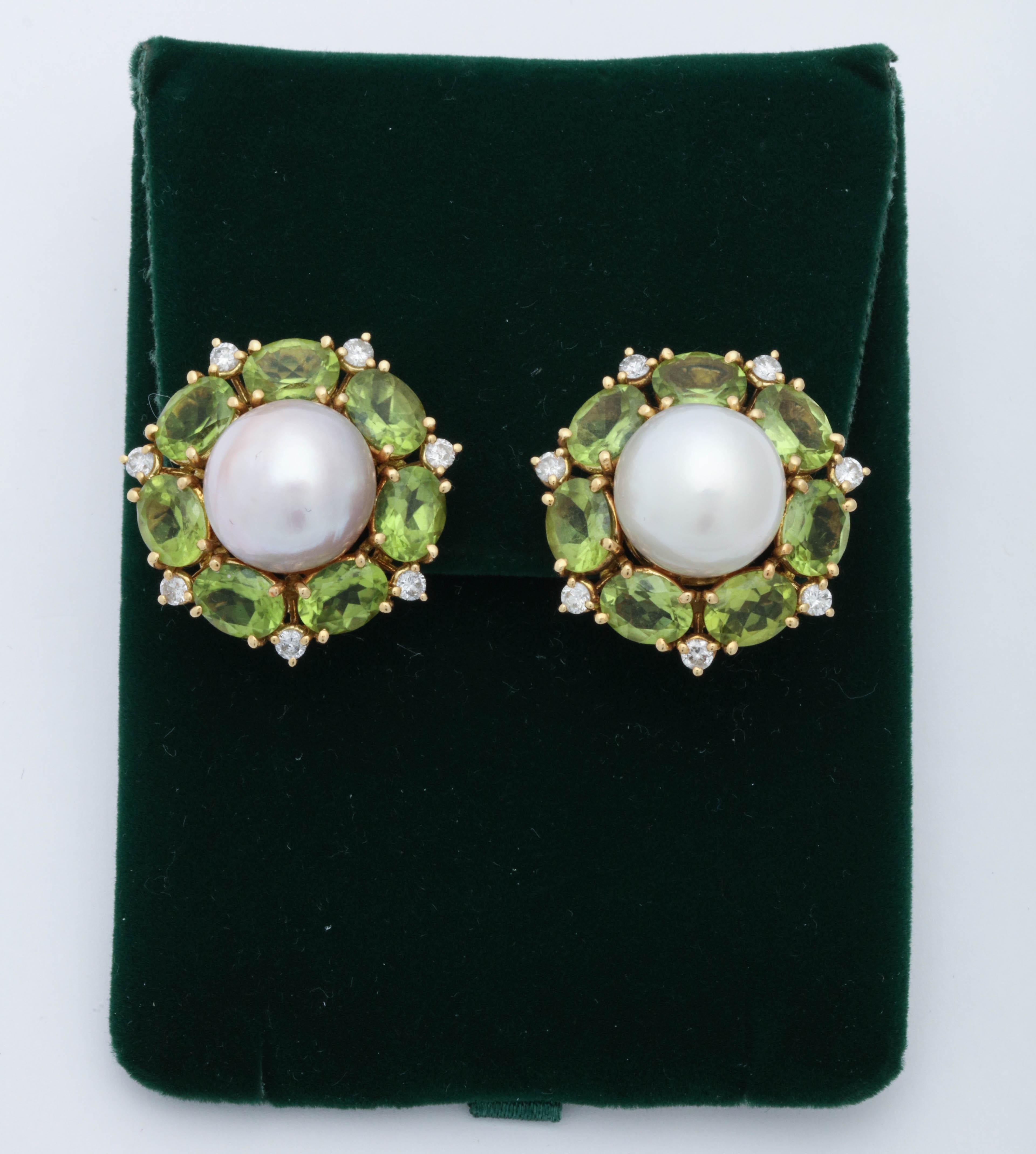 One Pair Of Ladies 18kt Yellow Gold Earclips Signed Seaman Schepps, Serial # 7541 Designed With Two South Sea Pearls Measuring Approximately 12MM Each And Further Surrounded By 14 Oval Shaped Faceted Peridots Weighing Approximately 28 Carats Total