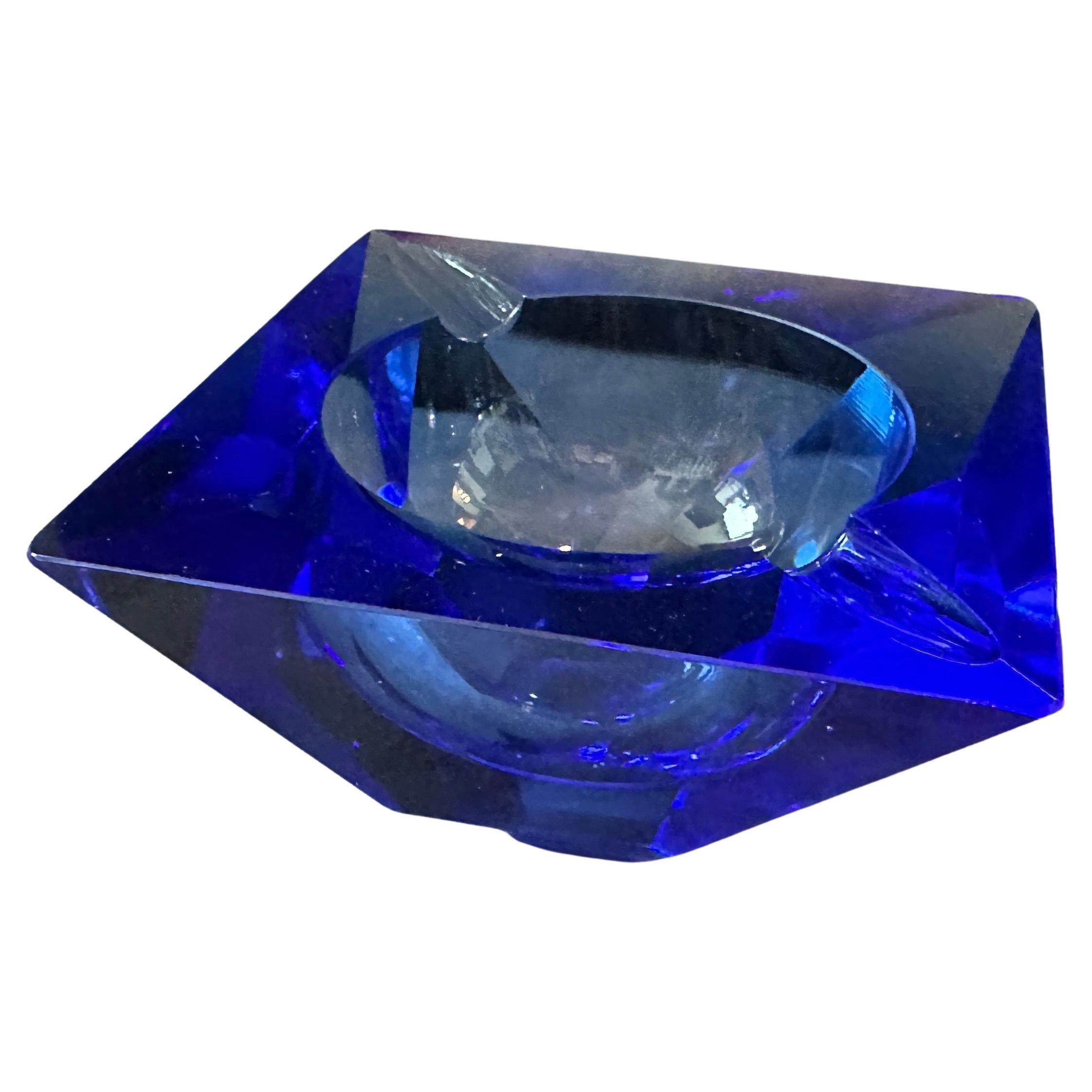 Questo posacenere in vetro di Murano blu sfaccettato è uno straordinario esempio di arte vetraria veneziana, che si rifà in particolare alle tecniche e all'estetica associate alla famiglia Seguso, uno dei più rinomati vetrai di Murano. La superficie