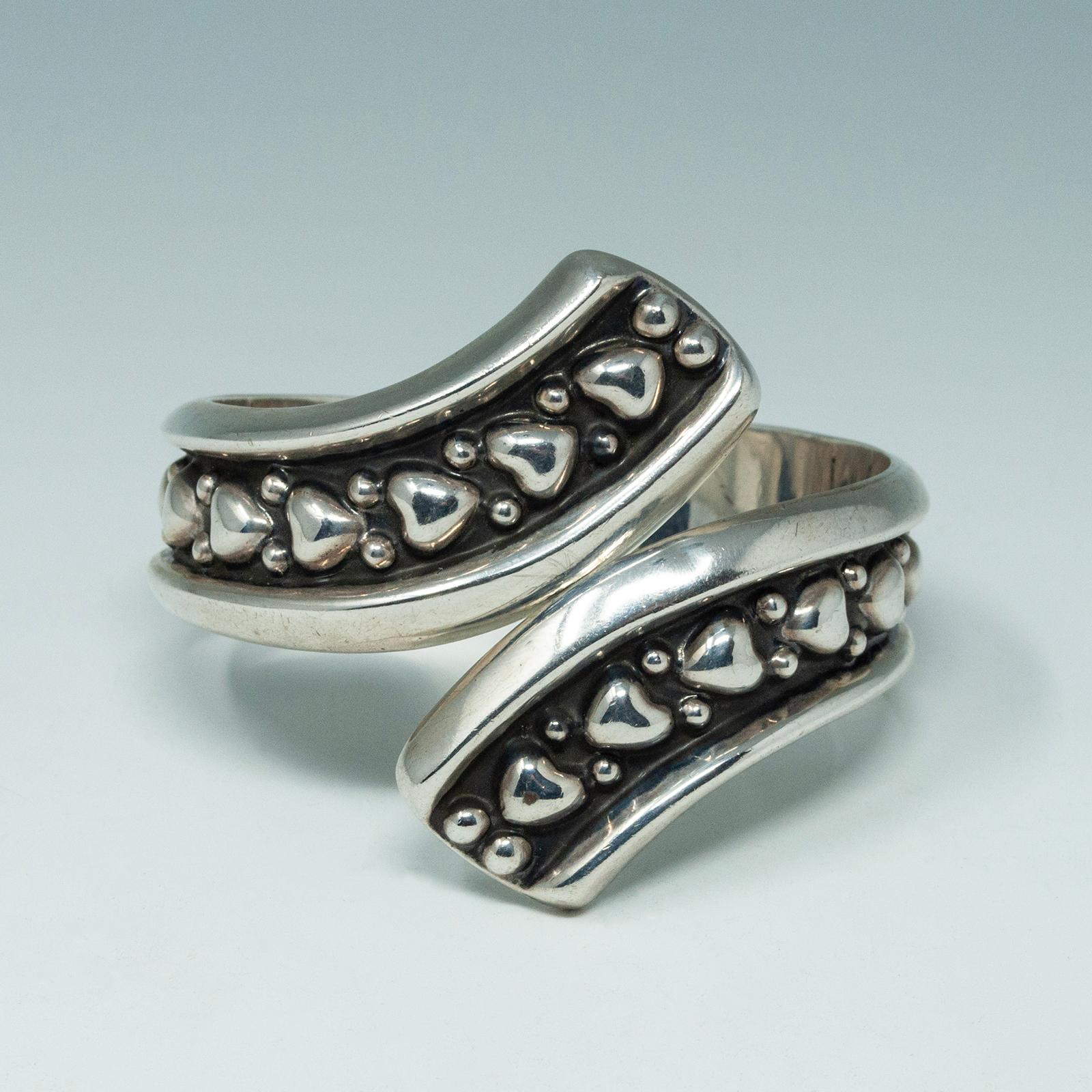 1980s silver clamper bracelet, Taxco, Mexico

This beautiful repoussé silver clamper bracelet is adorned with hearts and dots. The marks inside: each side of the clamper is marked TR-164 MEXICO 925, which indicates a Taxco origin.

The interior