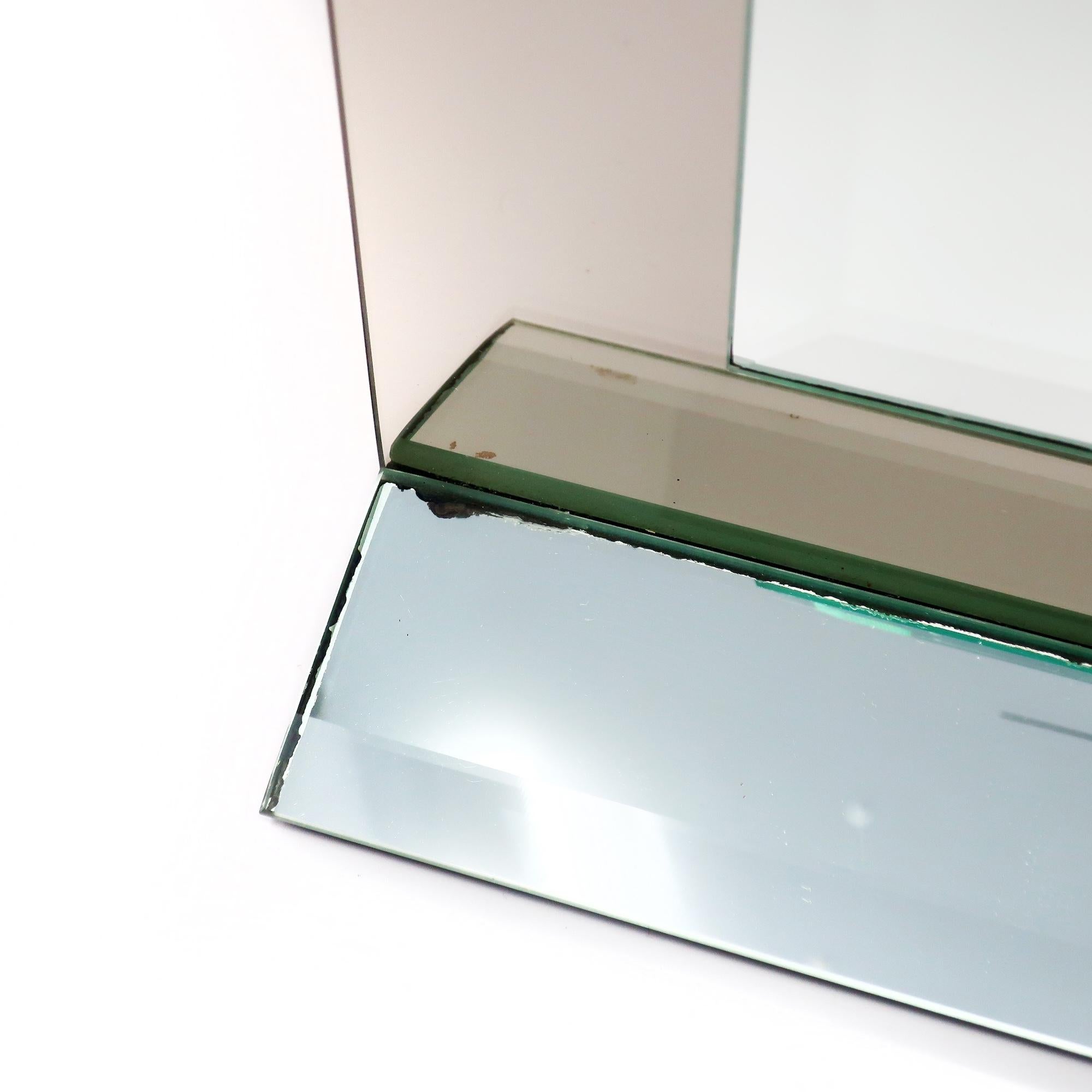 A stunning postmodern smoked glass and mirror table or mantle clock.  Triangular mirrored base with beveled edges and a mirrored face with a smoked glass border featuring rounded edges.  The design includes a round piece of mirror at 12 o'clock.

In
