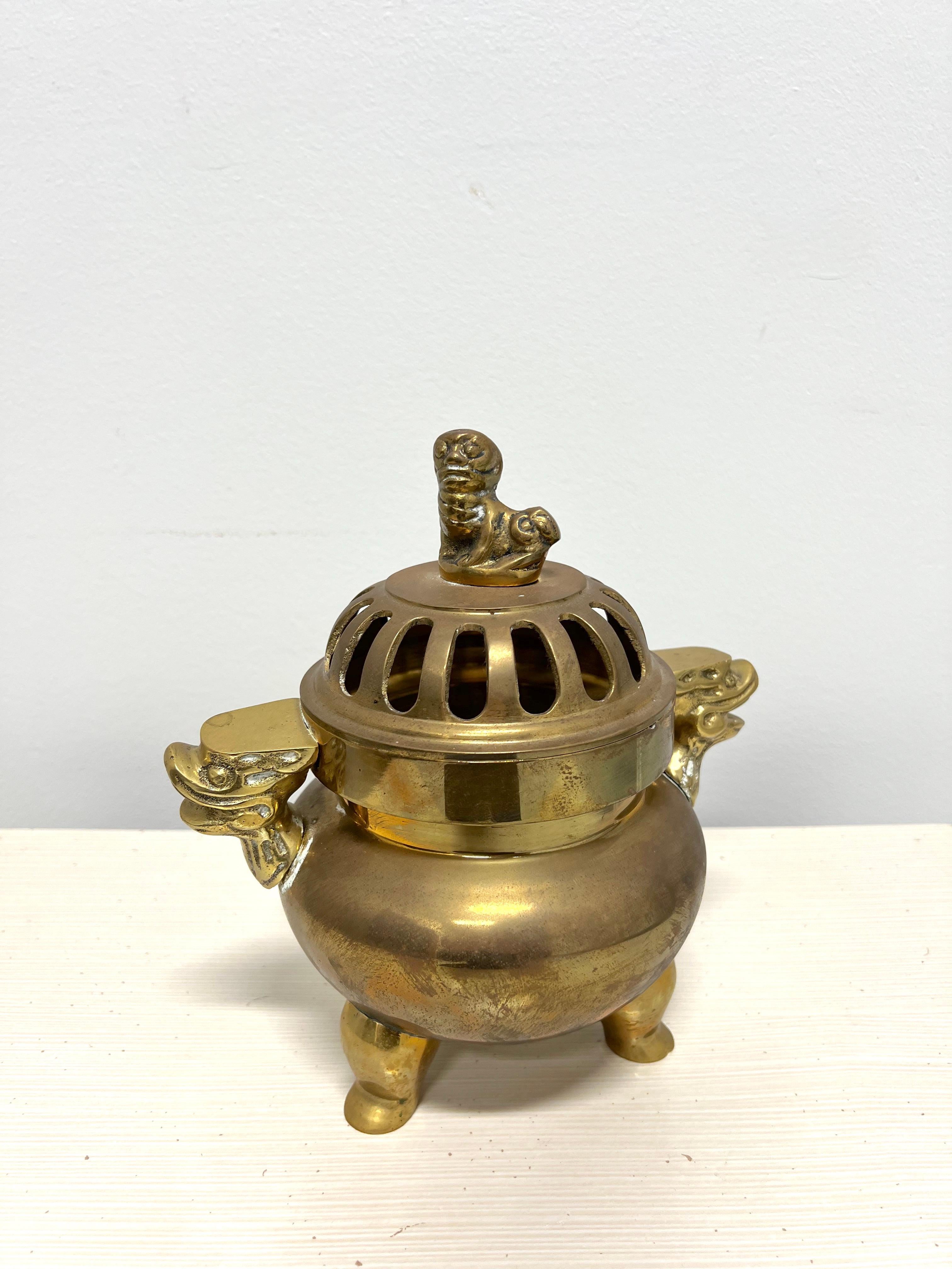 A vintage Chinese table top censer pot incense burner. Unsigned, artisan unknown. Solid brass of two pieces; round pot with serpent-like protruding handles & elevated on three legs, and an open design dome lid with dog-like top. Made in Hong Kong,