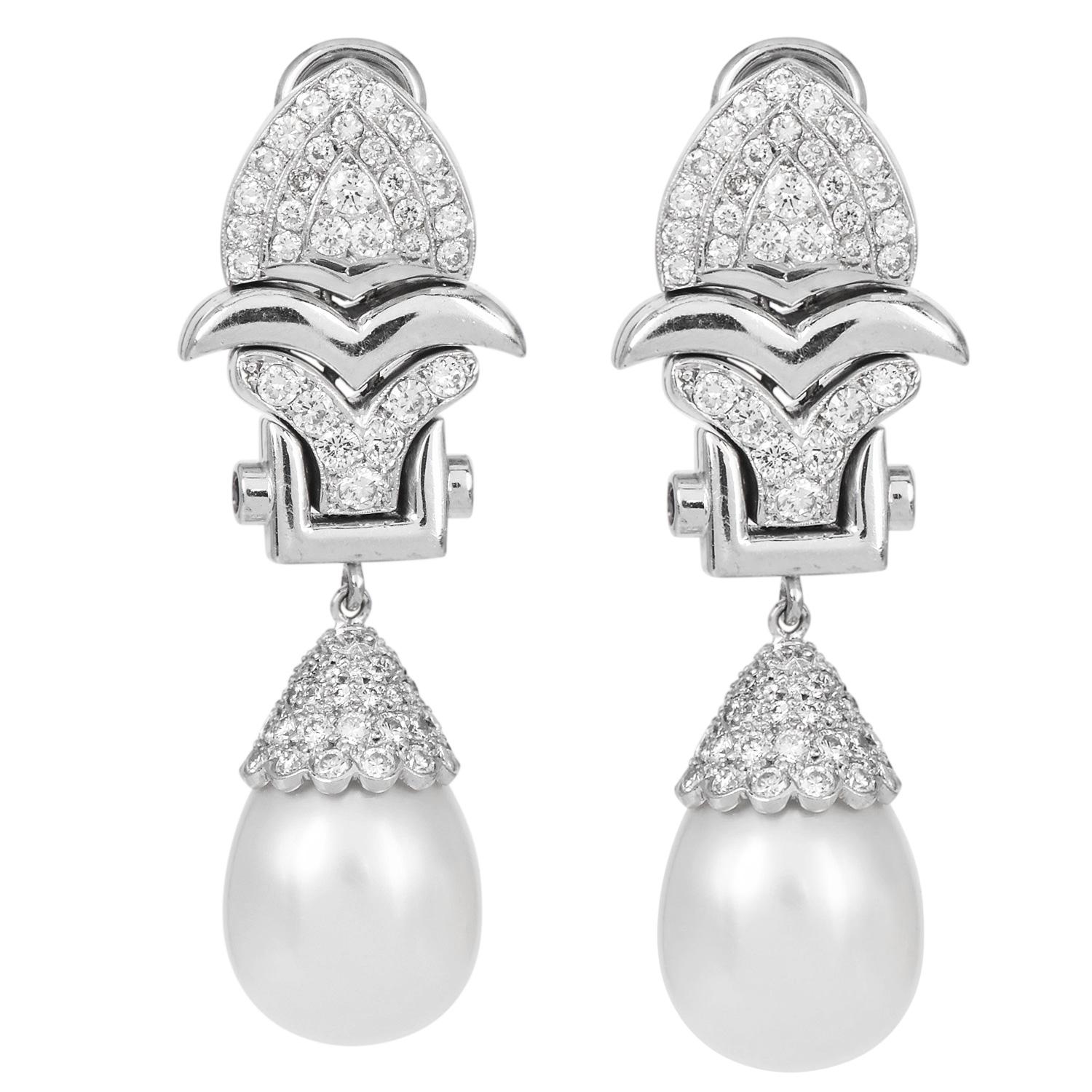 These platinum dangle earrings feature a lustrous South Sea pearl suspended from a scalloped design setting.

Each earring showcases a cascade of 168 natural round diamonds, meticulously set to enhance their radiance, with a combined weight of 3.38