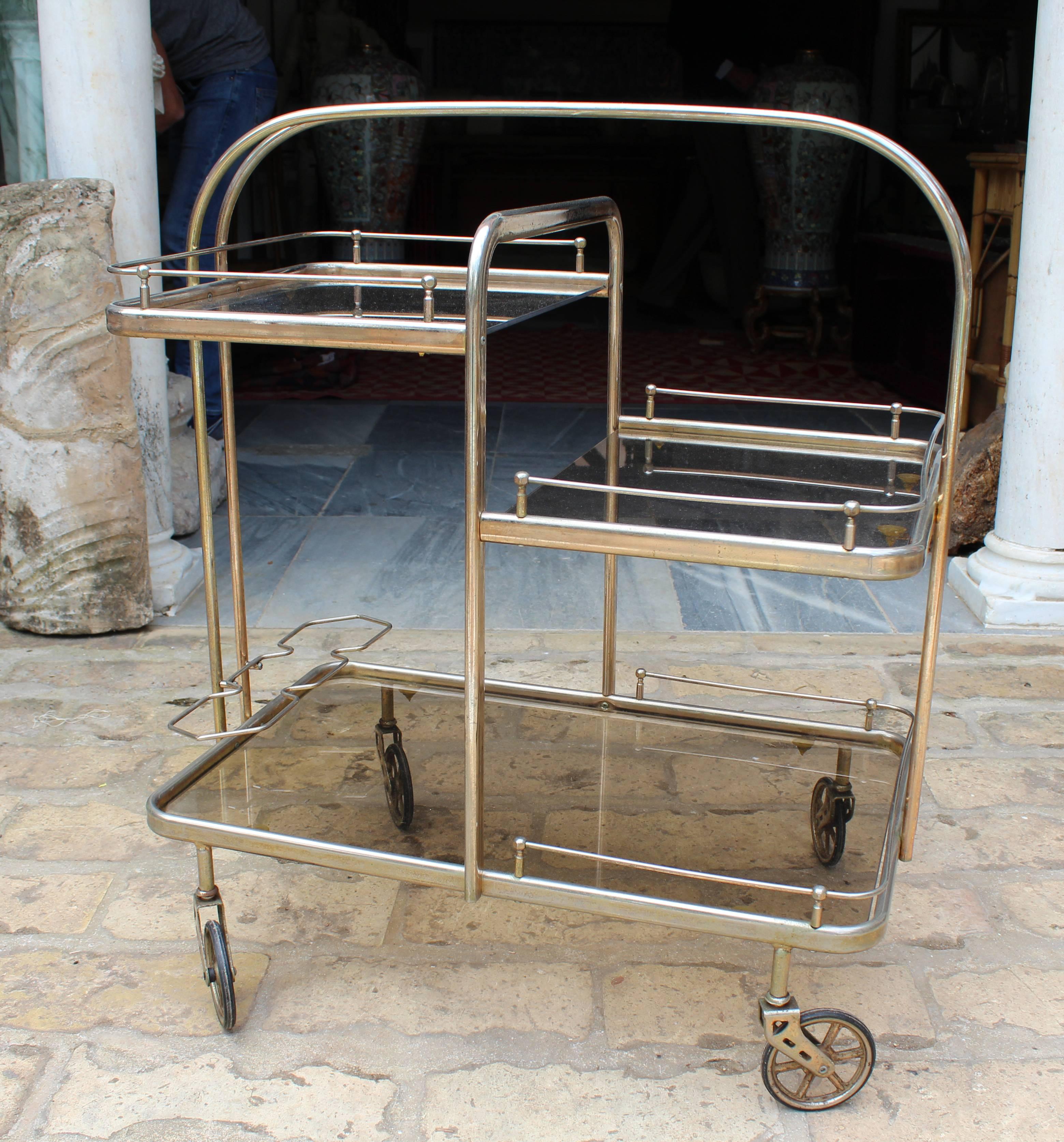 1980s Spanish gilded brass drinks trolley with original rubber wheels and vintage smoked glass trays.