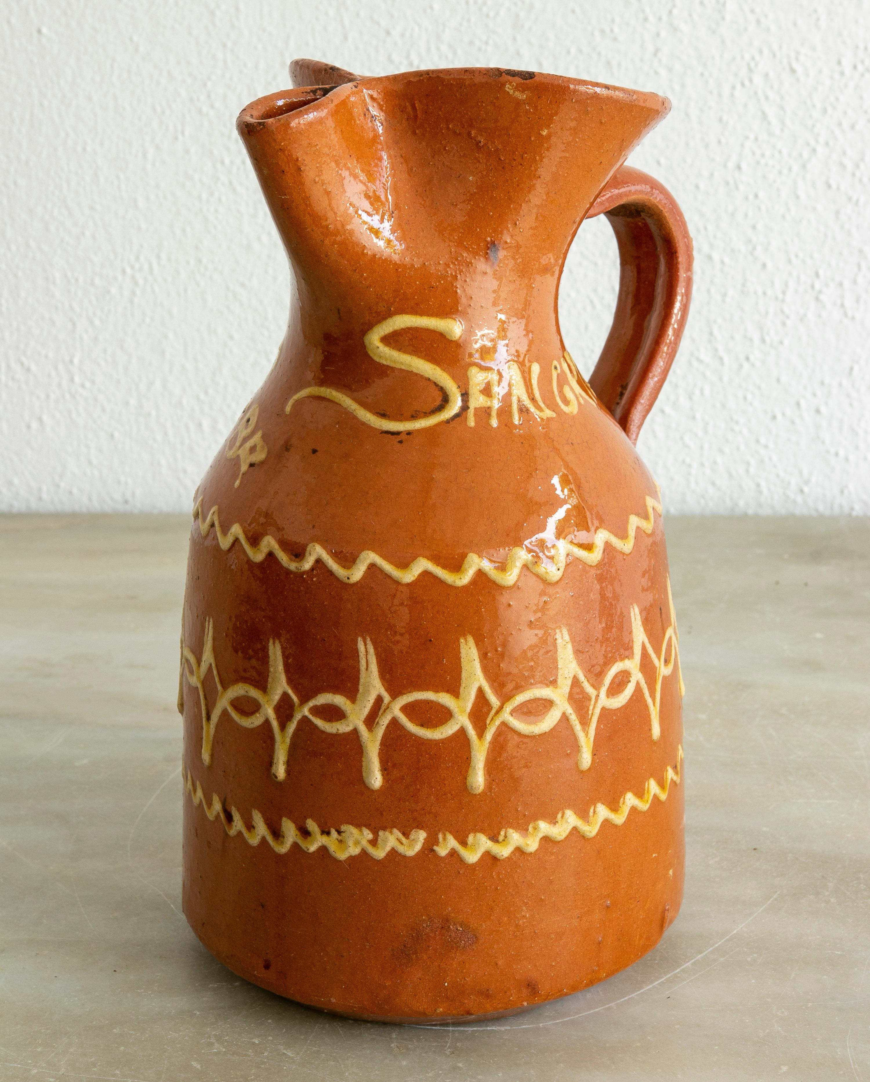 Jarra de cerámica esmaltada española vintage de los años 80 para sangría, una refrescante bebida veraniega hecha con una mezcla de vino, soda, zumo de limón, frutas peladas y cortadas y mucho hielo. 

Se lee 