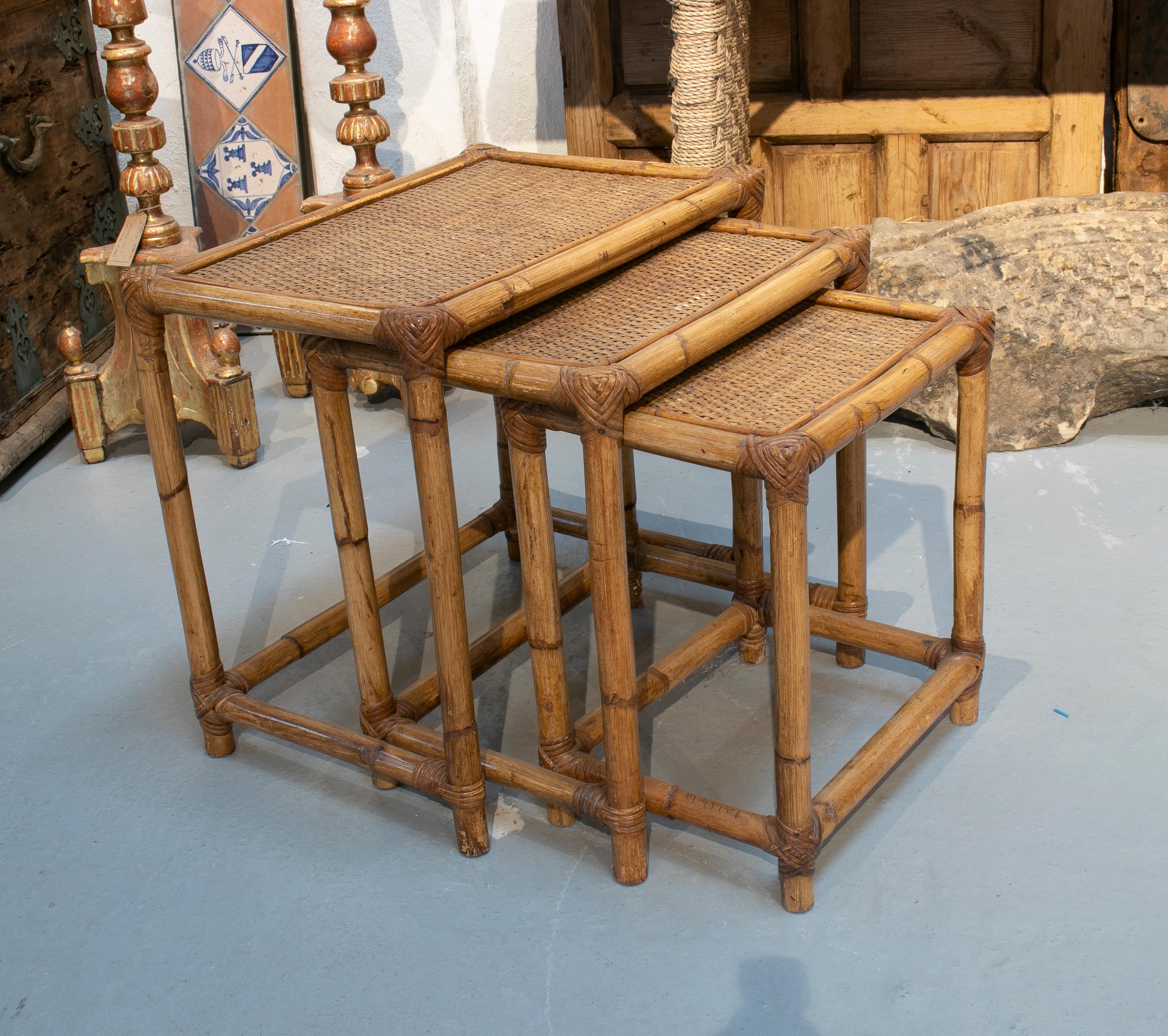 1980s Spanish set of three bamboo and rattan nesting tables.

Measures: Big table: 50 x 53 x 36cm
Median table: 46 x 45 x 31cm
Middle table: 42 x 37 x 28cm.