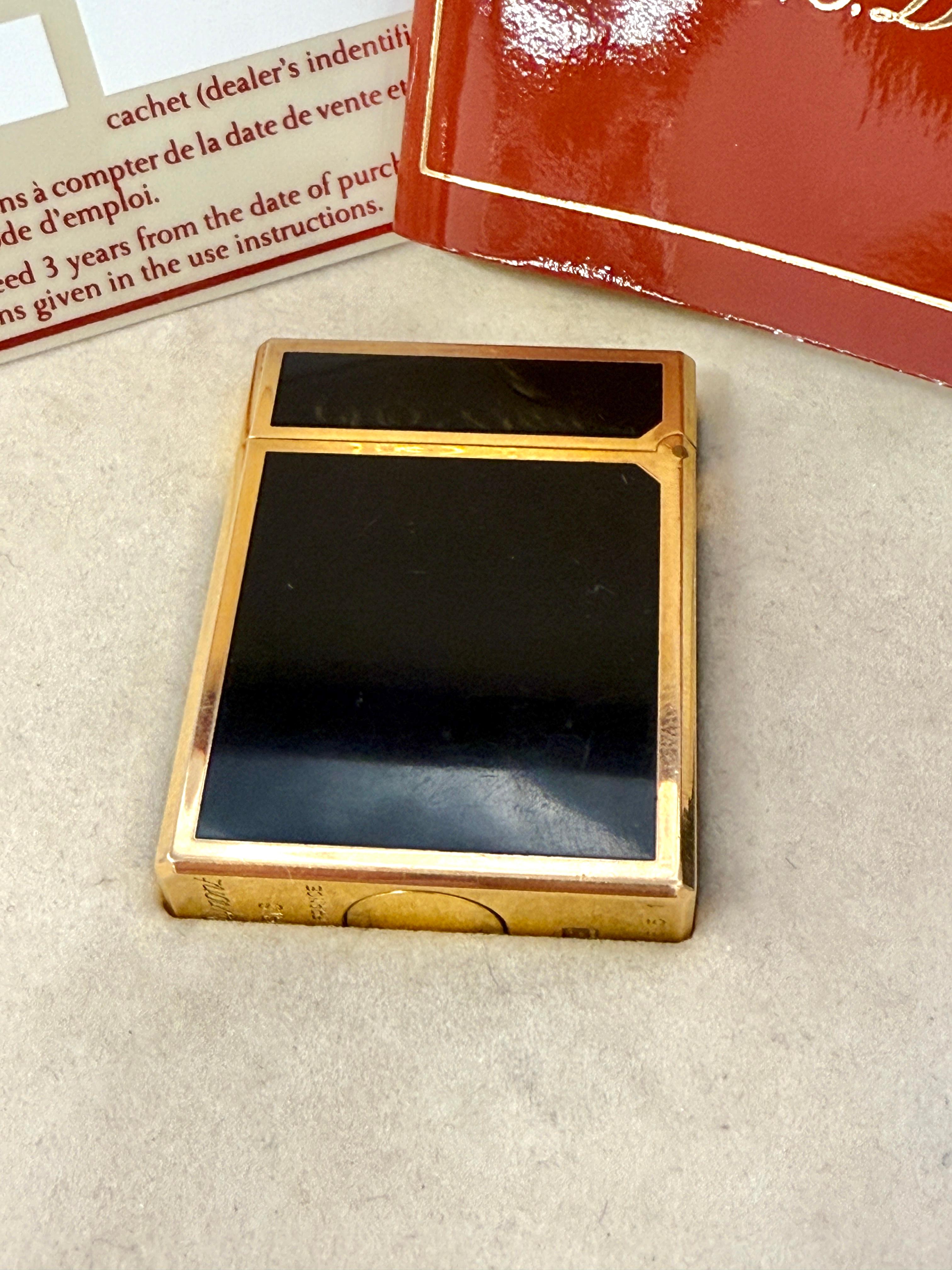 A pretty S.T. DuPont Lighter in gold plate and Laque De Chine, Chinese Lacquer.  The lighter has its original box and instruction manual, and guarantee card. It shows a purchase date of 1989. The lighter is in working condition as you can see as in