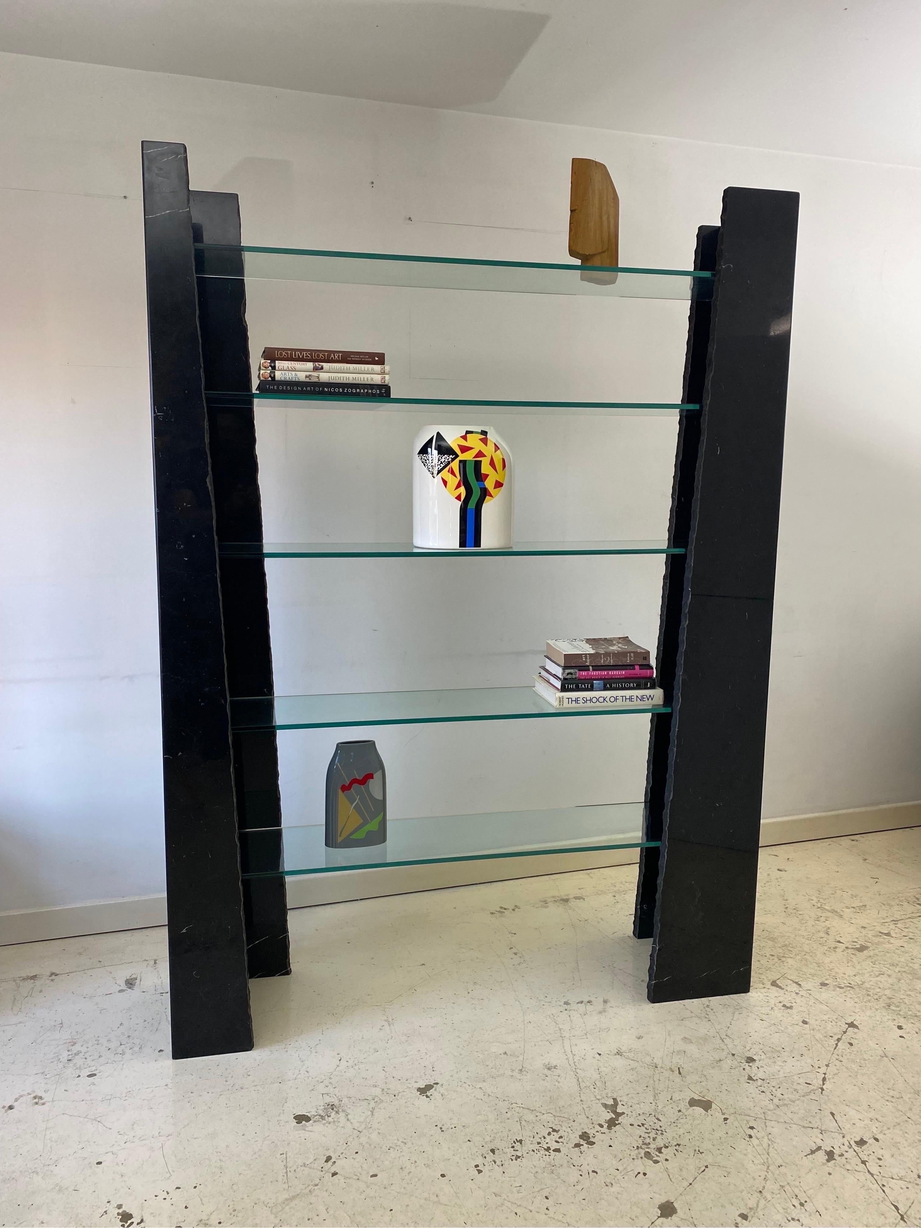 An impressive and monumental shelving unit in black carrara marble with asymmetrical raw edges and clear tempered glass. This piece has been made in late 1980s early 1990s by Stone International S.P.A. This shelving unit has been imported from Italy
