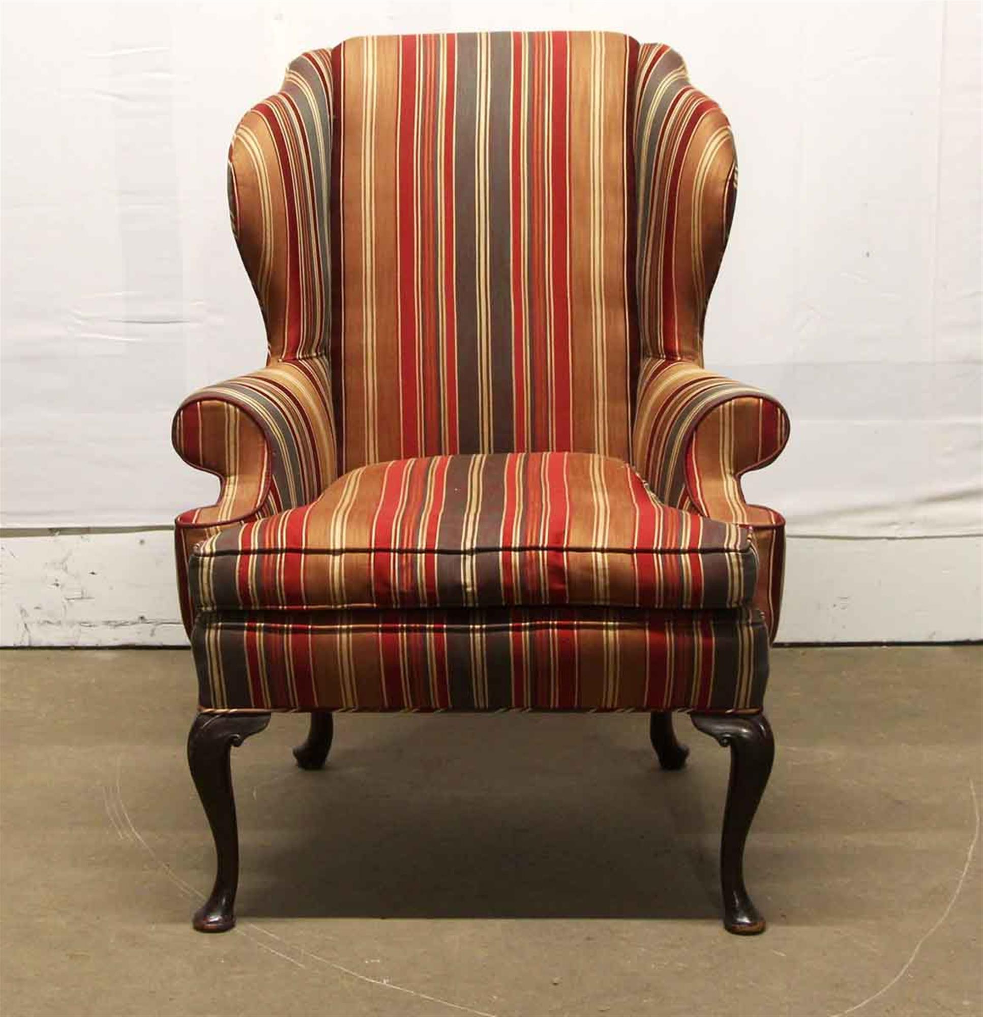 Wing back chair with red, tan and brown stripes and dark tone carved wooden cabriole legs. The wood has some scratches and will need minor refinishing. This can be seen at our 400 Gilligan St location in Scranton, PA.