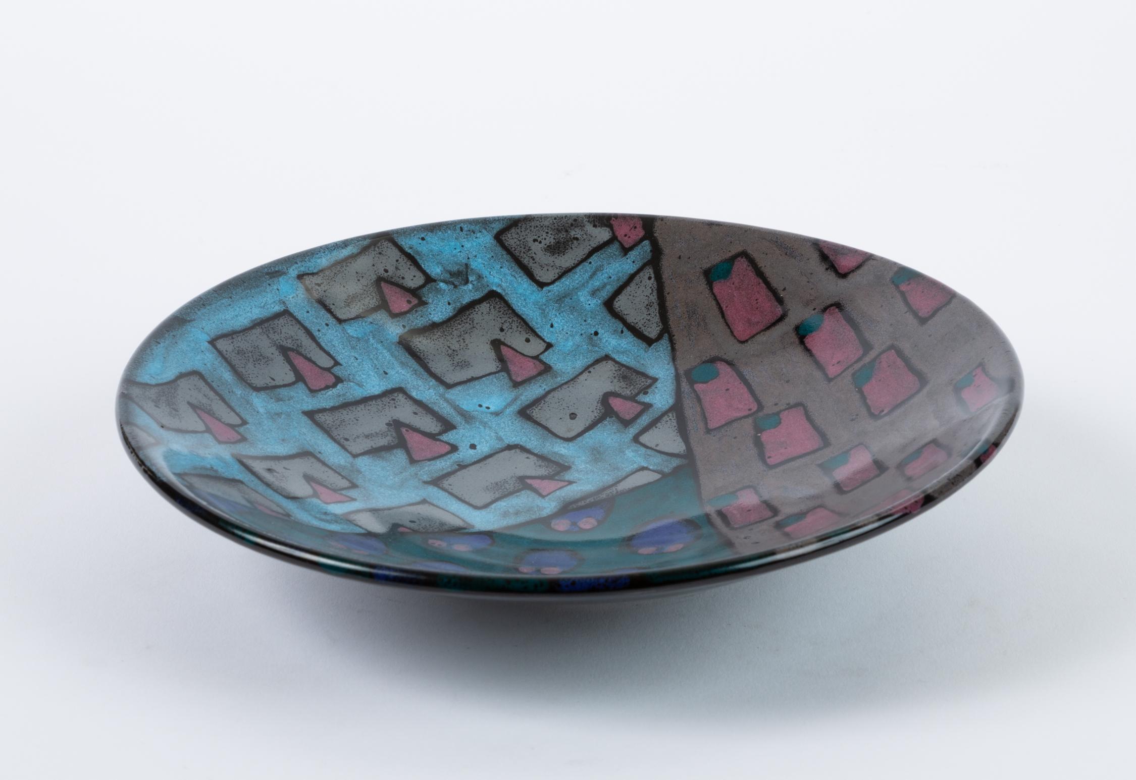 A 1980s studio pottery decorative bowl or vide-pôche with a sharply angled sides and a geometric motif in a color palette of muted jewel tones. Reminiscent of Dorothy Hafner’s celebrated designs for Rosenthal, the bowl features three competing