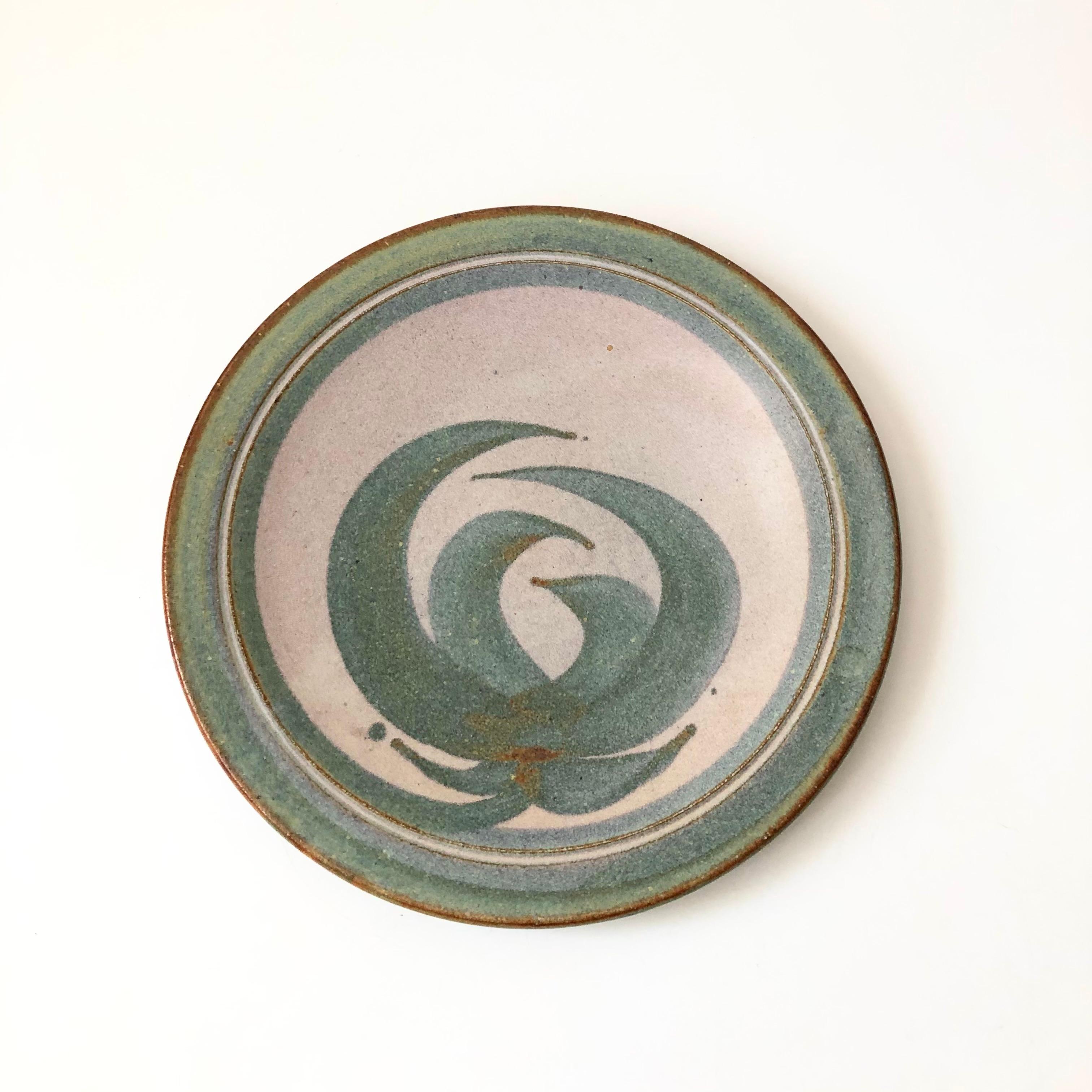 A large vintage studio pottery plate with a beautiful hand painted floral design in the center. Perfect for using as a large serving or decorative tray. Finished in pale purple and blue-green glazes. Signed by the artist on the base and dated 1982.

