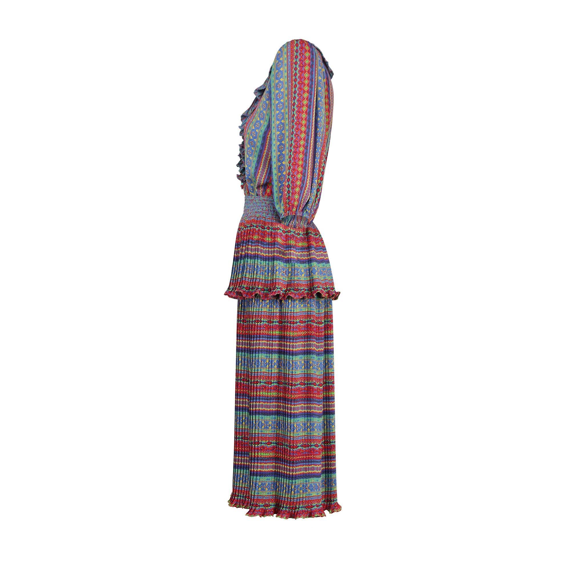 Made in the USA, this vivacious dress was designed by Susan Friar in the late 1970s to early 1980s. Beloved for her outlandish prints during this era, this dress showcases a bold rainbow-hued print of geometric patterns which form stripes along the