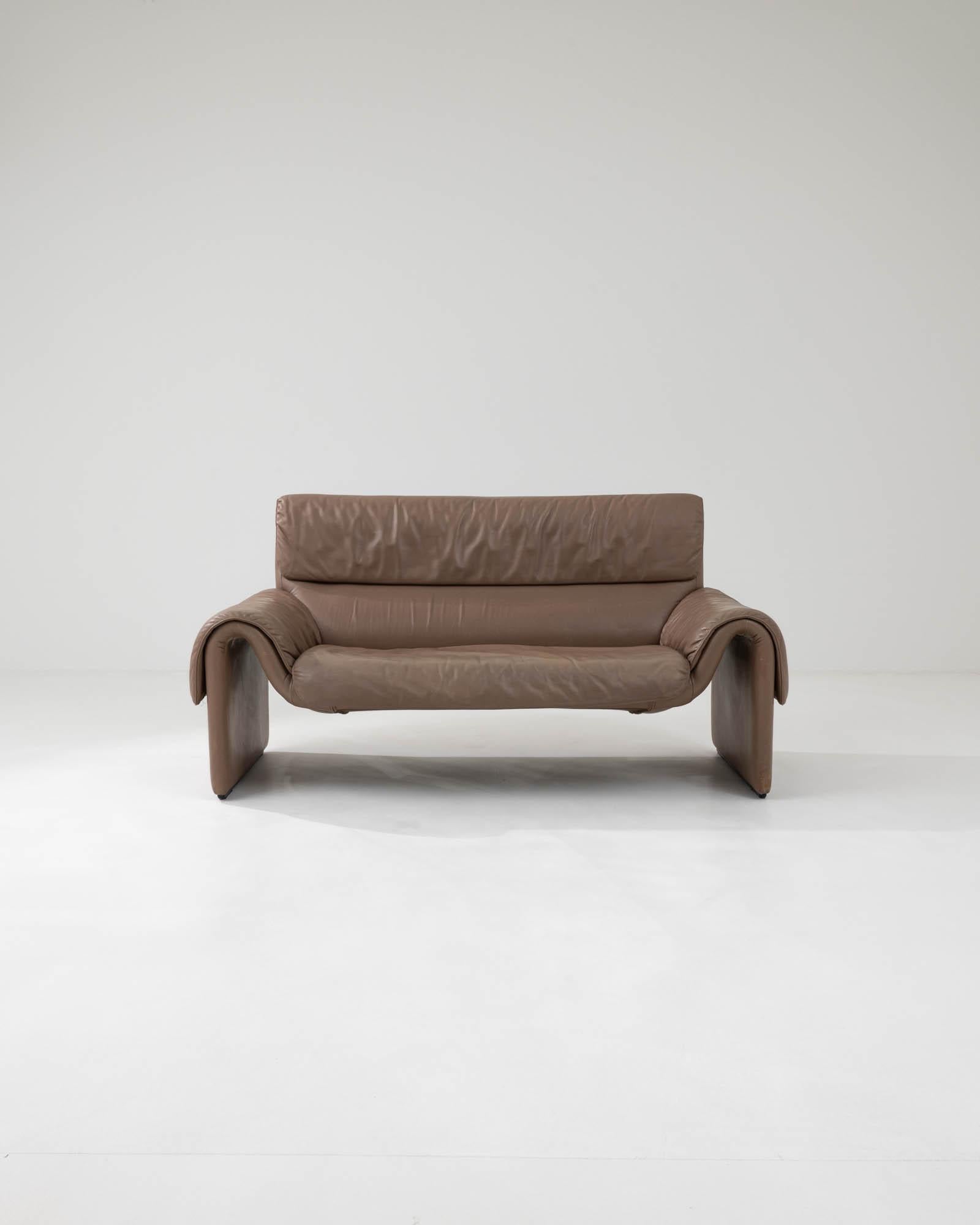 The captivating interplay of unconventional shapes and sleek materials defines the DS2011 sofa, a creation by the iconic Swiss brand De Sede from the 1980s. Draped in high-quality taupe-toned leather, this piece showcases exquisite contours in the