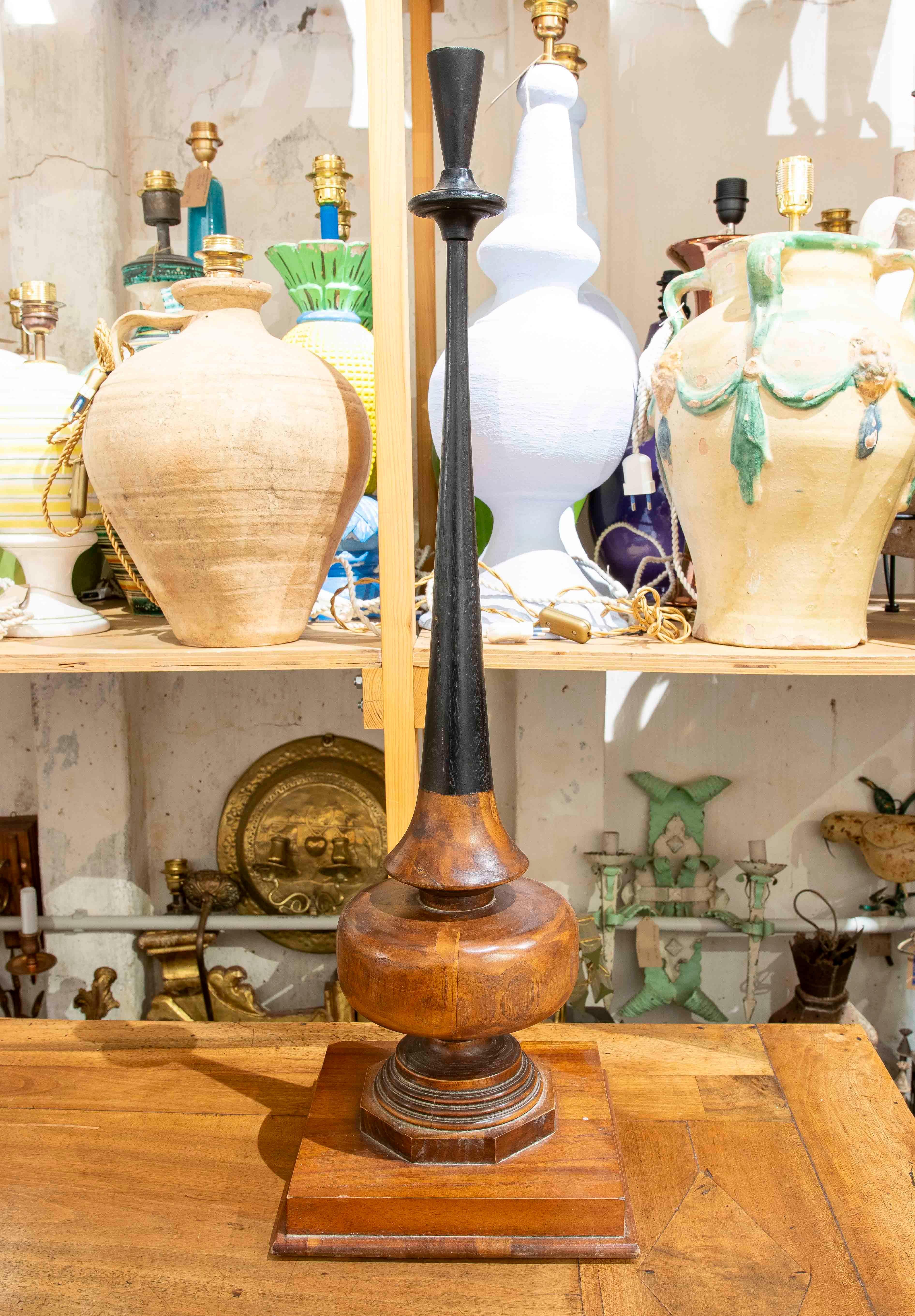 Elegant table lamp with a turned wooden base and elongated body in matt black wood finish. This design combines the warmth of wood with the modernity of black wood, creating a unique and sophisticated piece that adapts perfectly to contemporary and