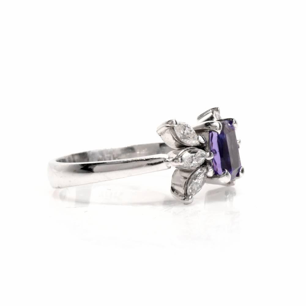 This estate engagement ring designed by and signed Muzo is crafted in 18 karat white gold, weighing 5.3 grams and measuring 7 mm wide x 4 mm high. This alluring ring is centered with a cushion-cut tanzanite,weighing 0.90 carats, complemented by 6